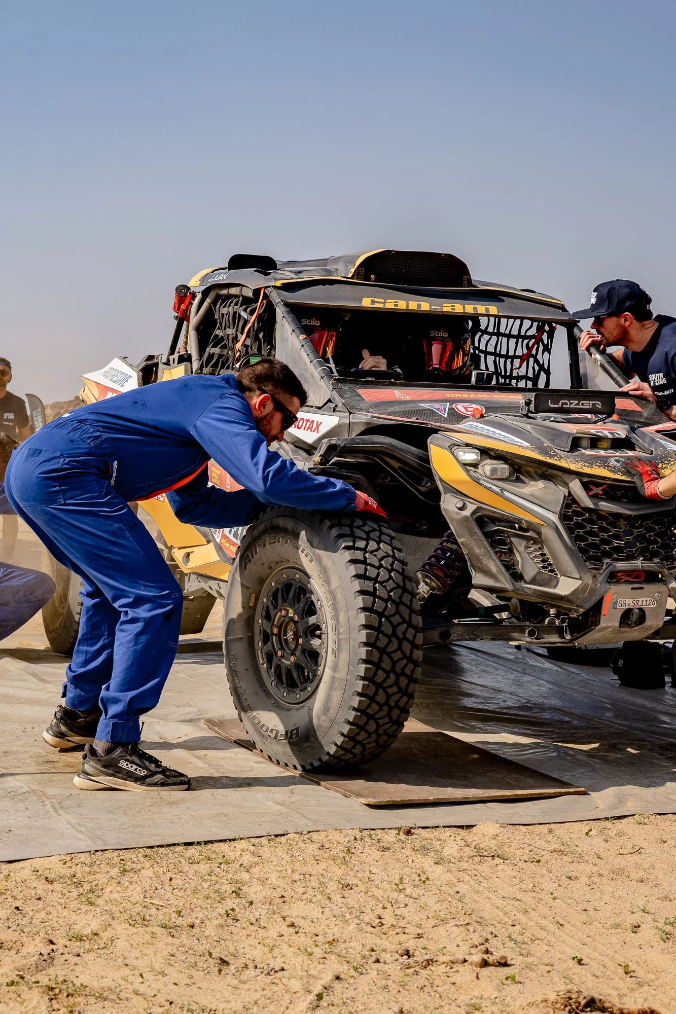 Mechanic in blue overalls checking a wheel on a Can-Am race car