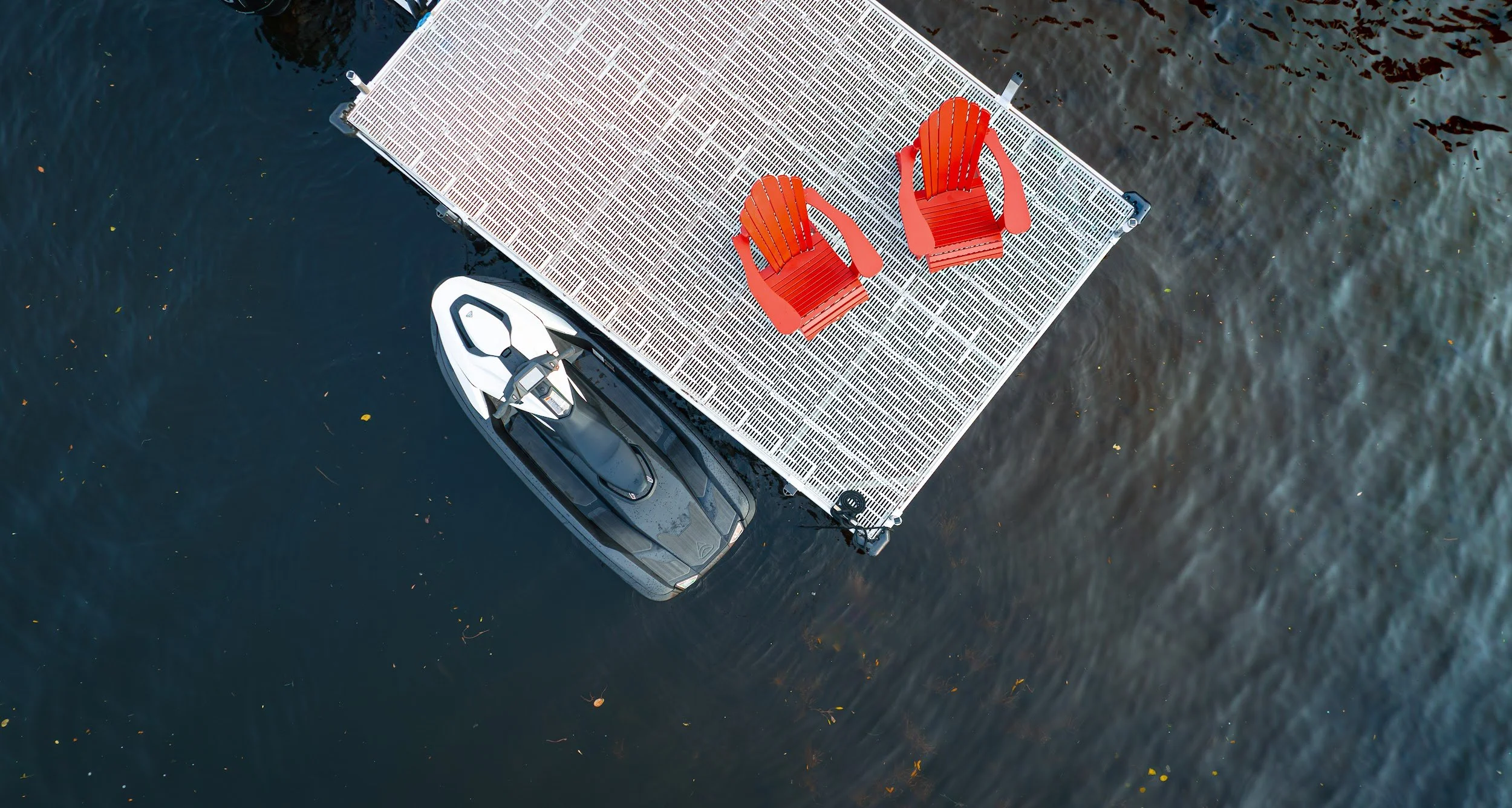 Aerial view of a Taiga Orca moored at a floating dock with two red chairs