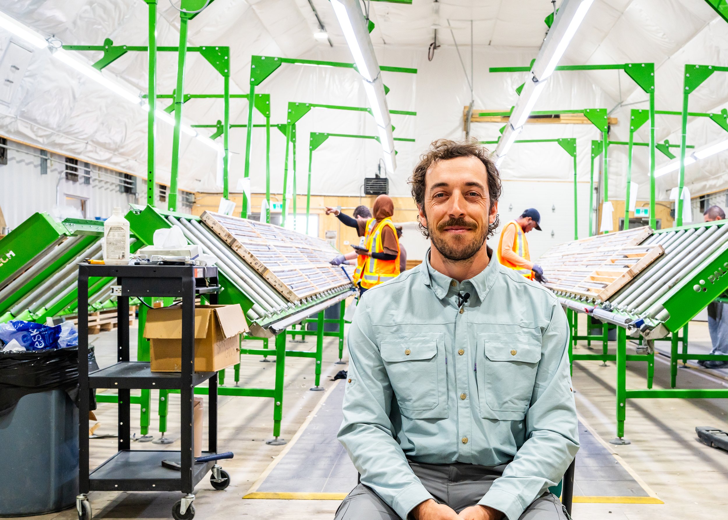 Worker seated in the core shack, rows of core boxes behind him