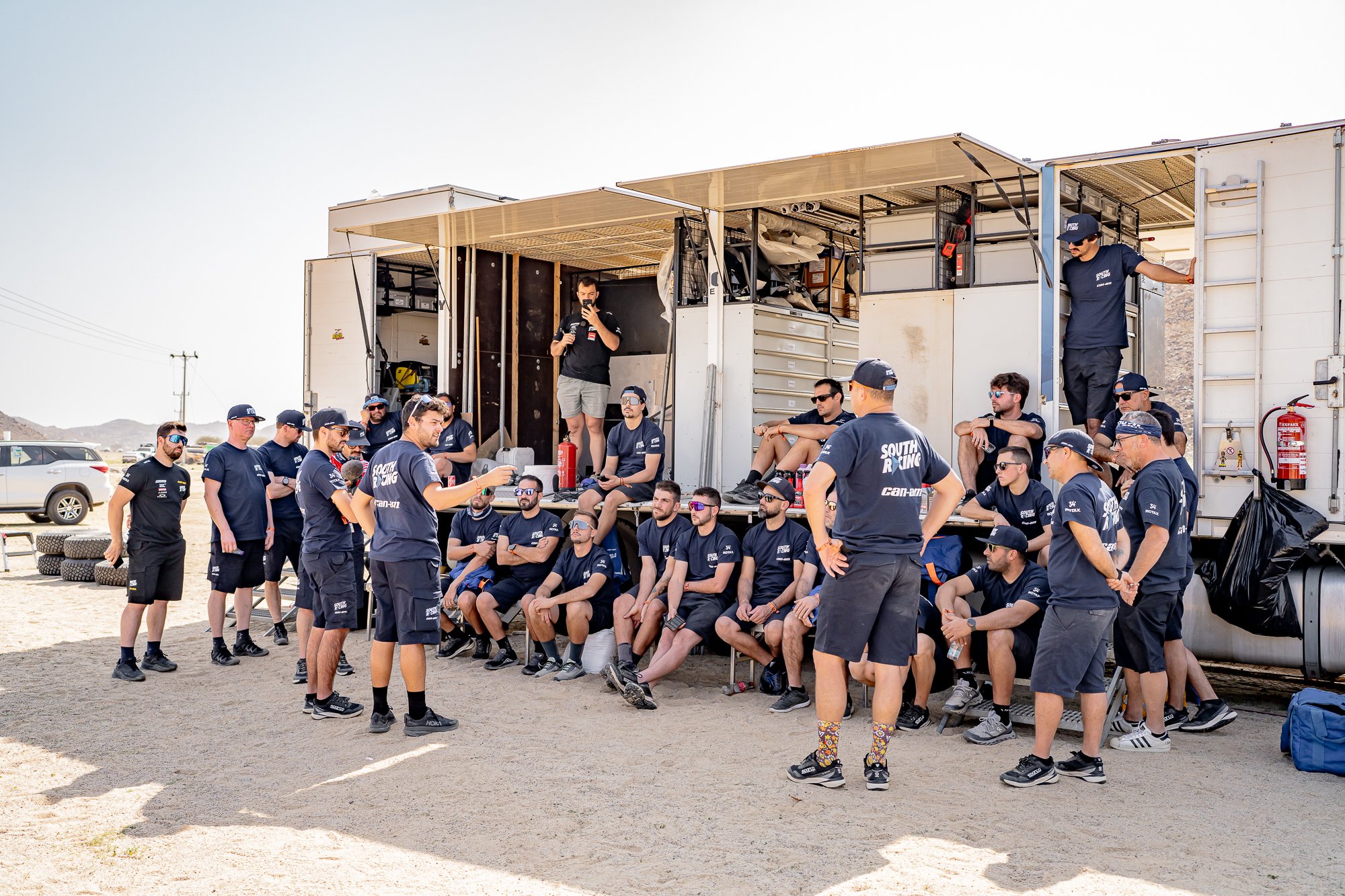 Team briefing in front of the service trucks at the bivouac