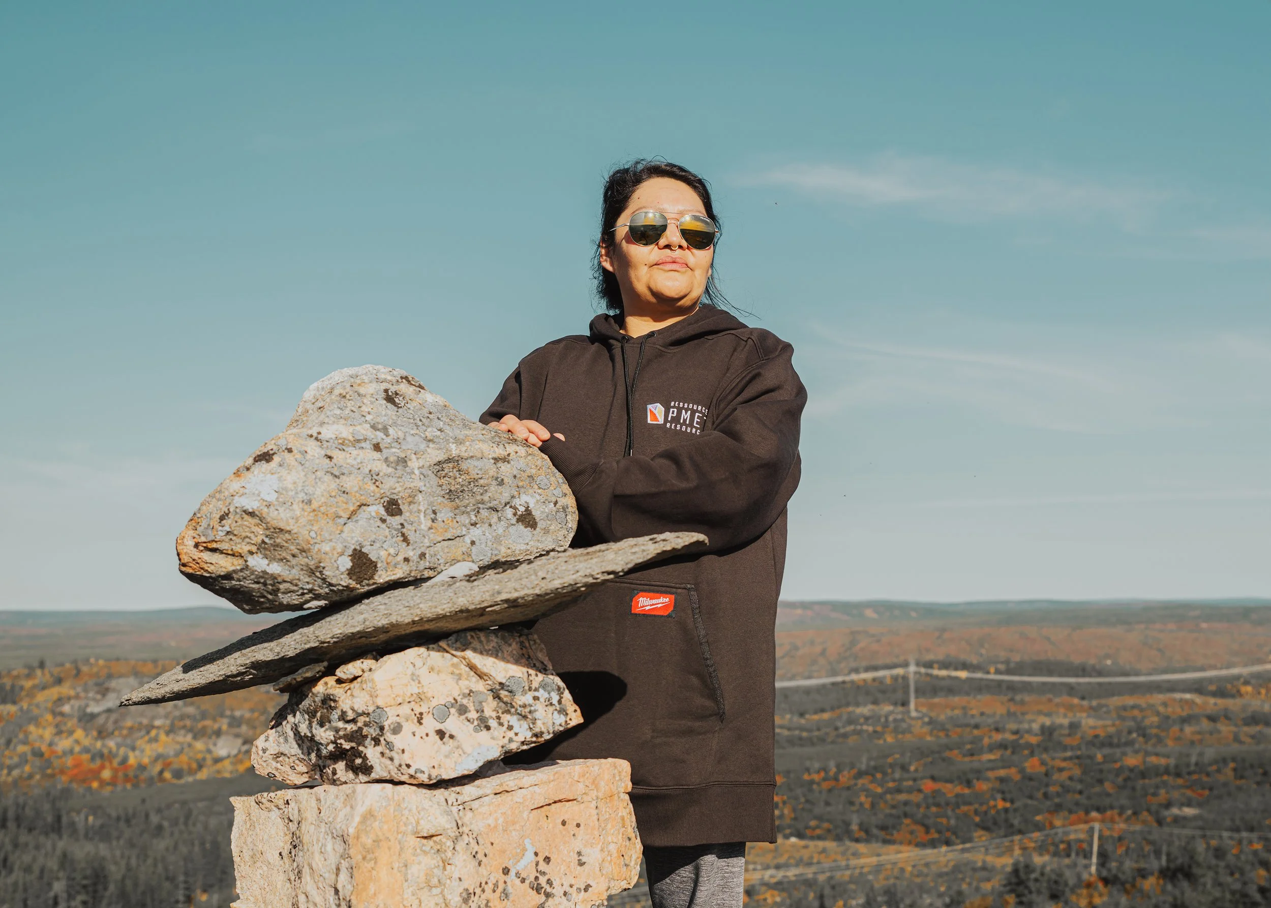 Woman beside a stone inukshuk above the autumn taiga
