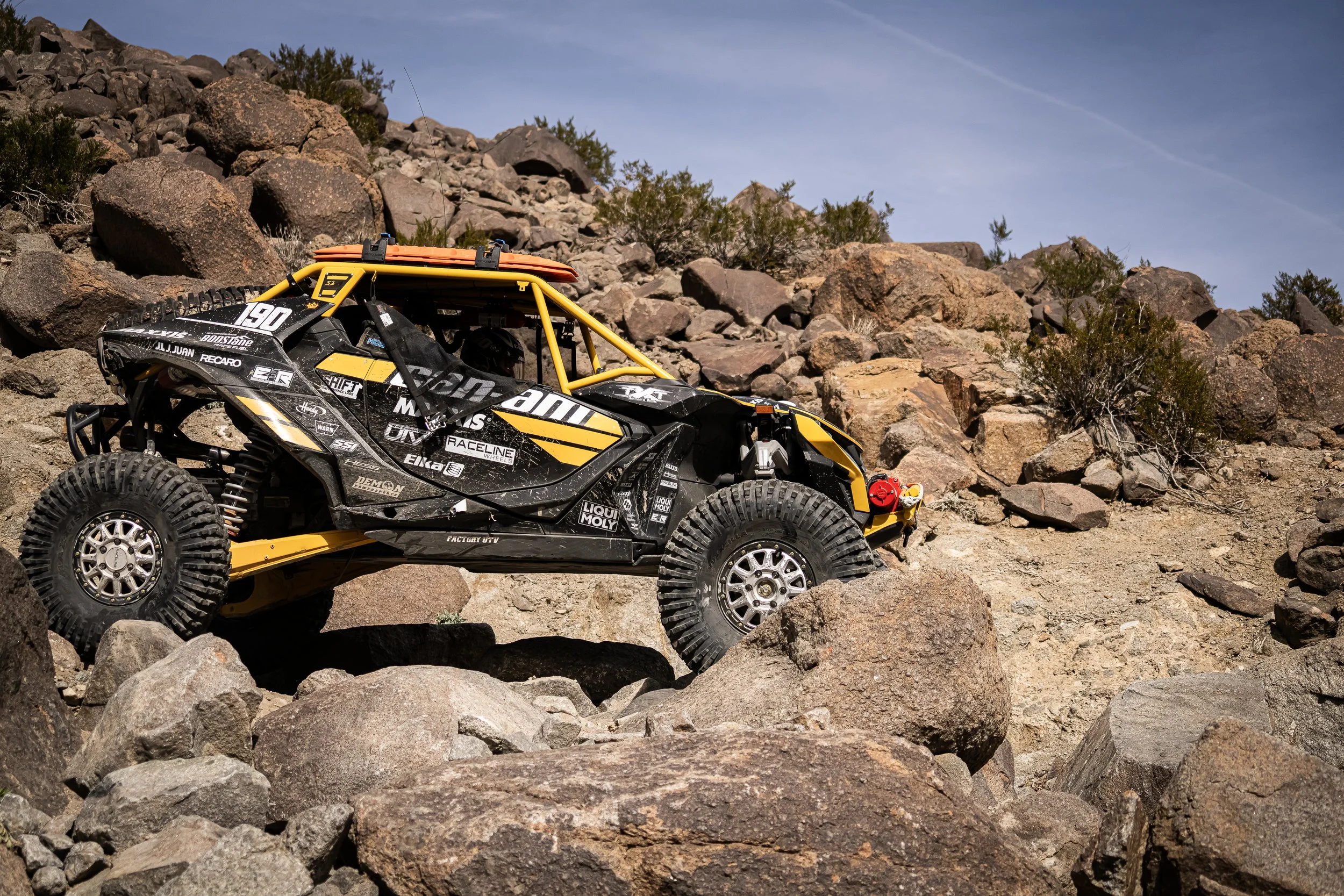 Can-Am side-by-side in black and yellow race livery crawling over boulders at King of the Hammers