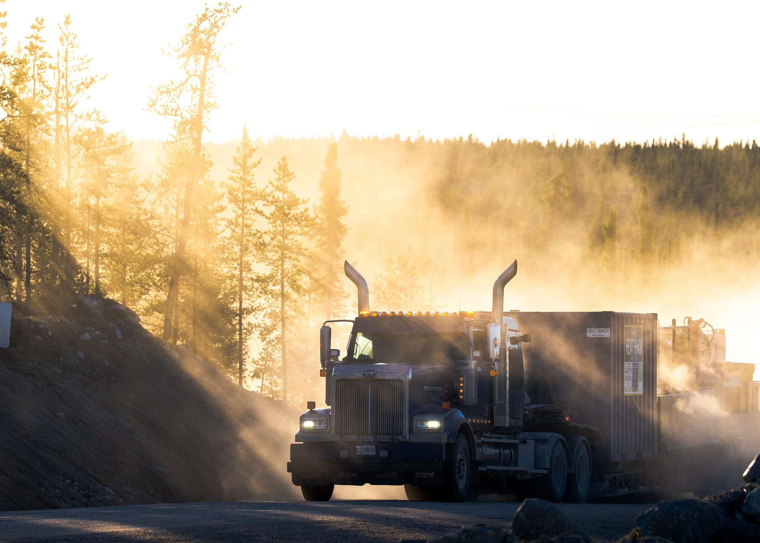 Transport truck in golden dust on the camp road at sunrise