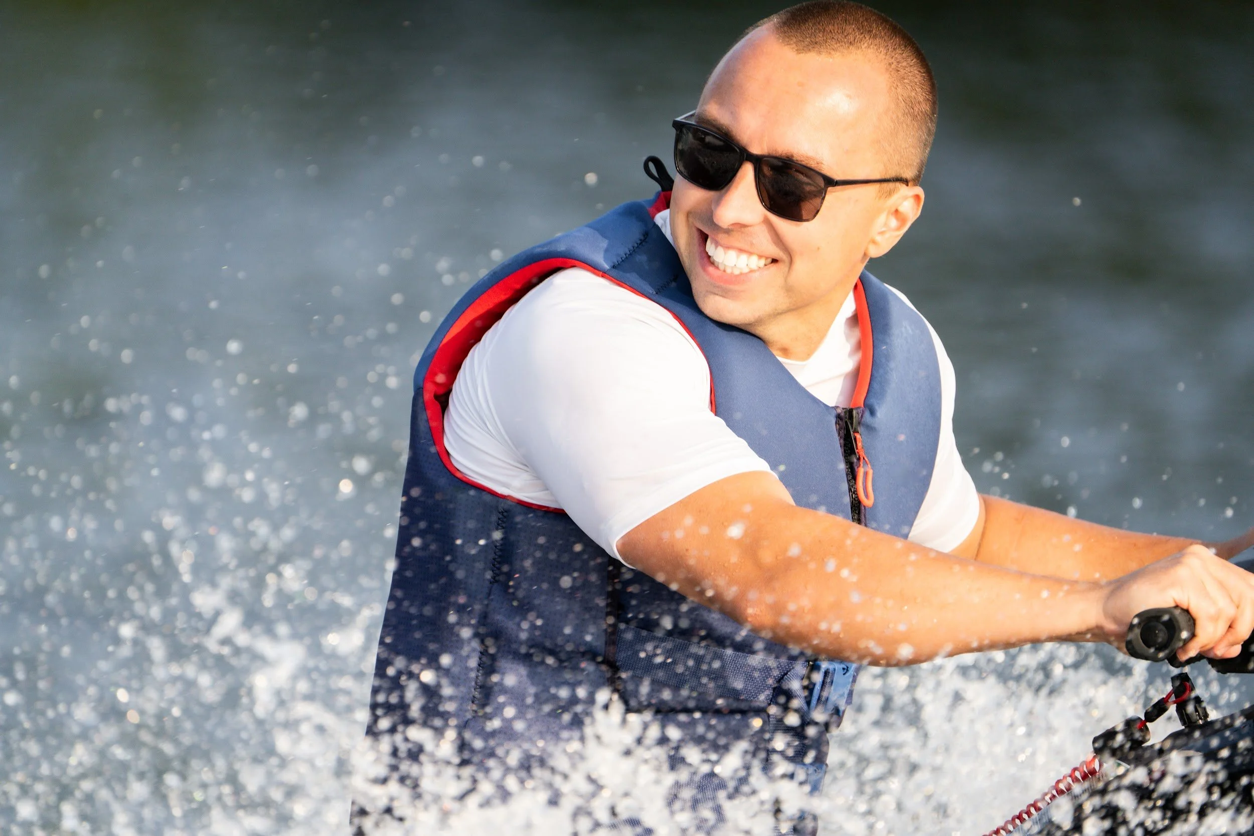 Rider in a blue life vest laughing through the spray