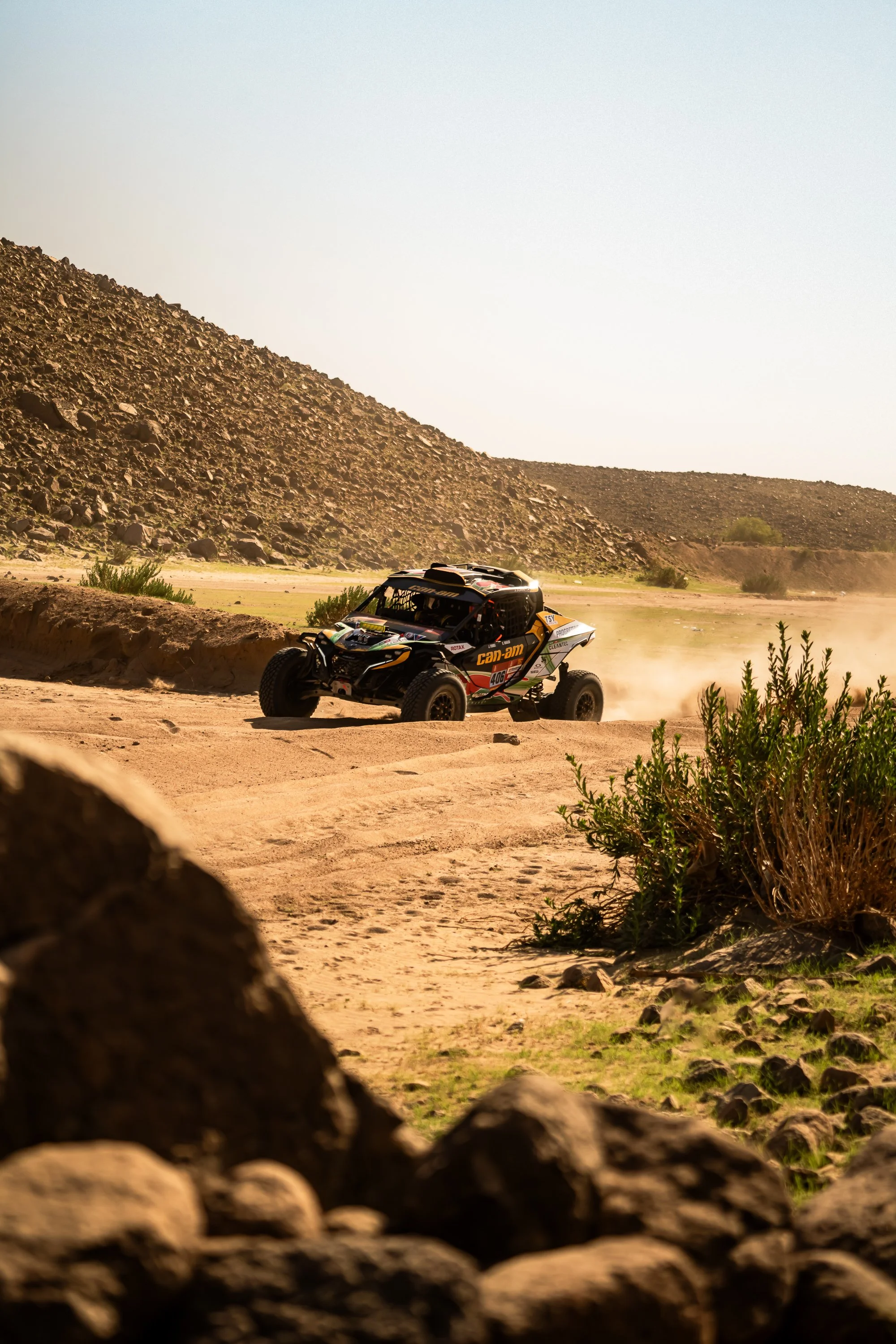 Can-Am race car on a dusty track through rocky hills