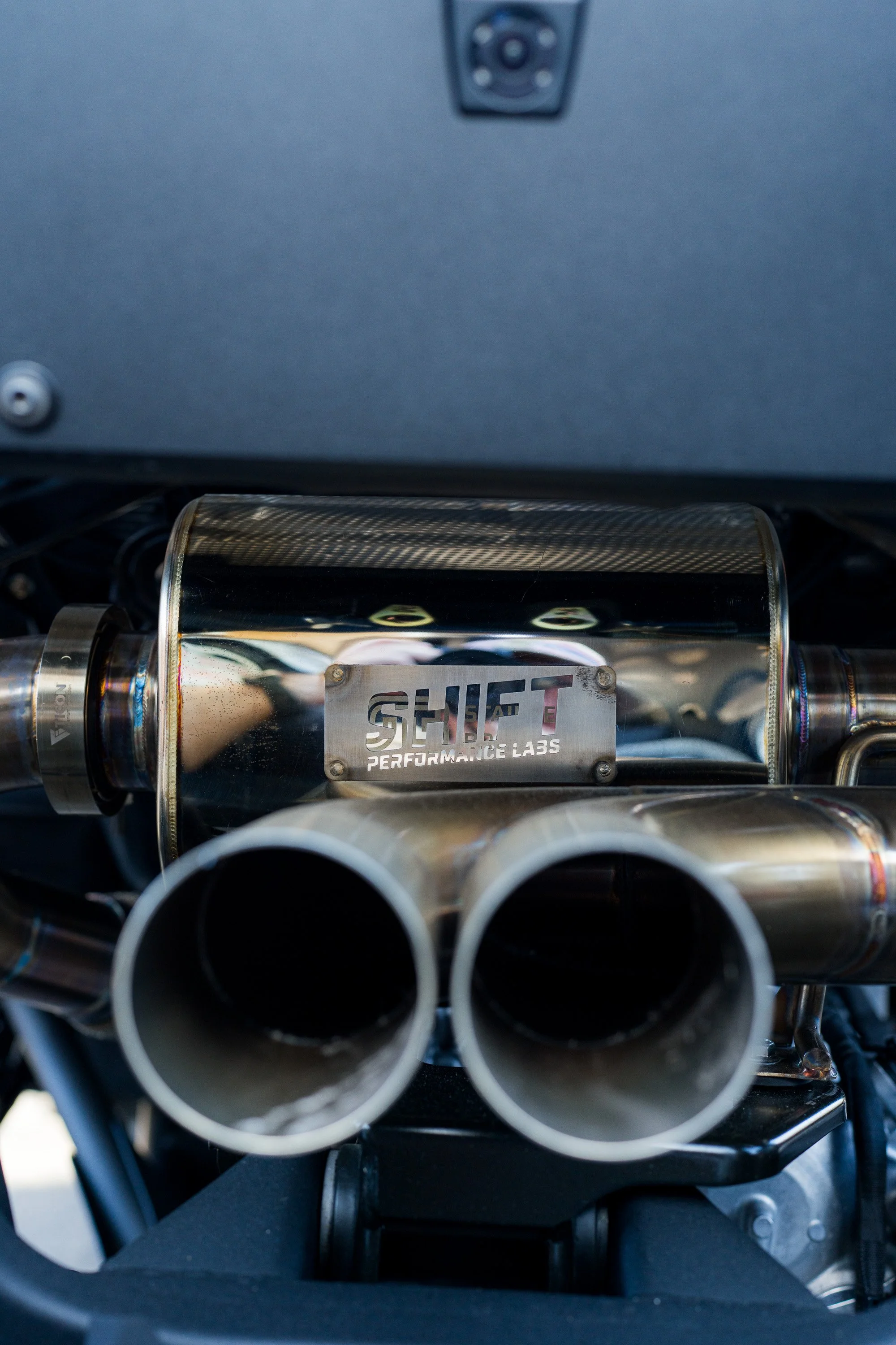 Twin exhaust tips with a Shift badge on a side-by-side
