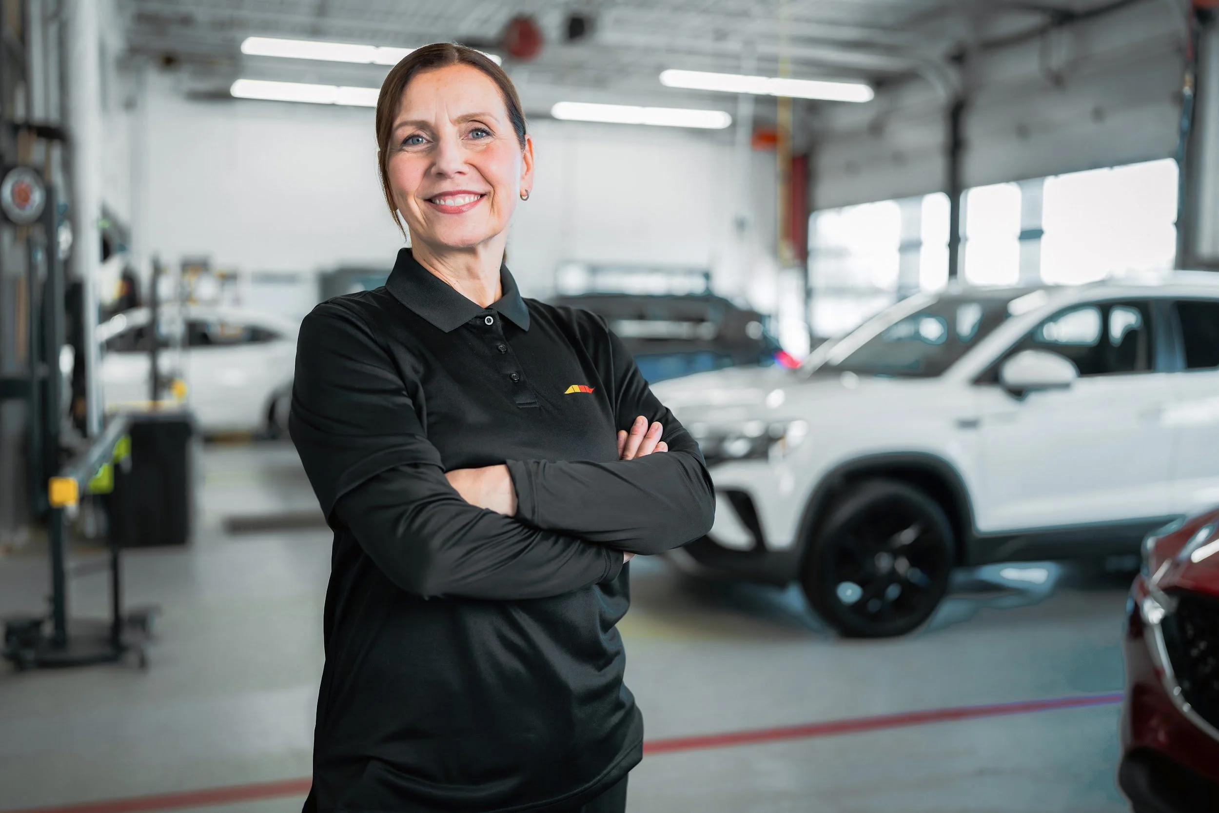A Lebeau technician in the shop, a white SUV on the floor behind her