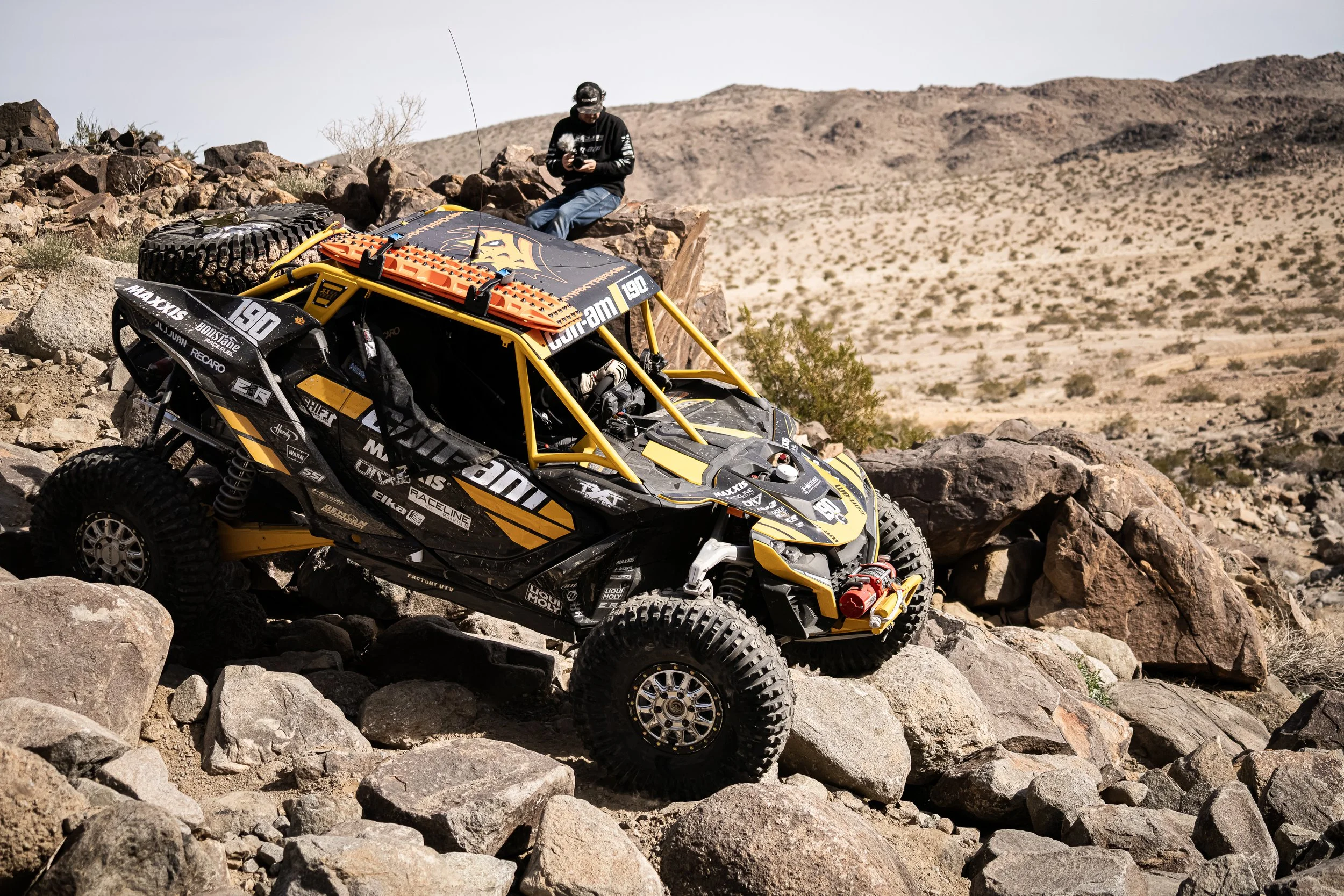 Can-Am side-by-side descending a rock field in Johnson Valley, a spectator watching from above