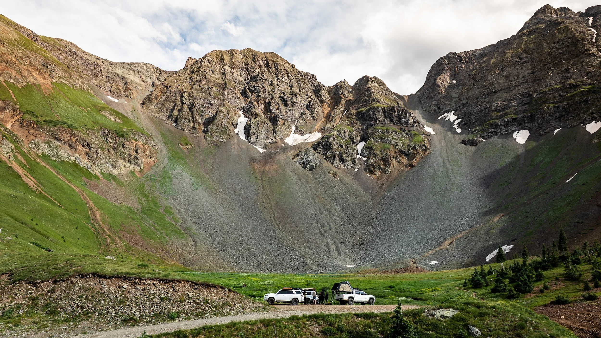 Aerial view of the three Toyotas parked in an alpine basin under snow-streaked peaks in Colorado.