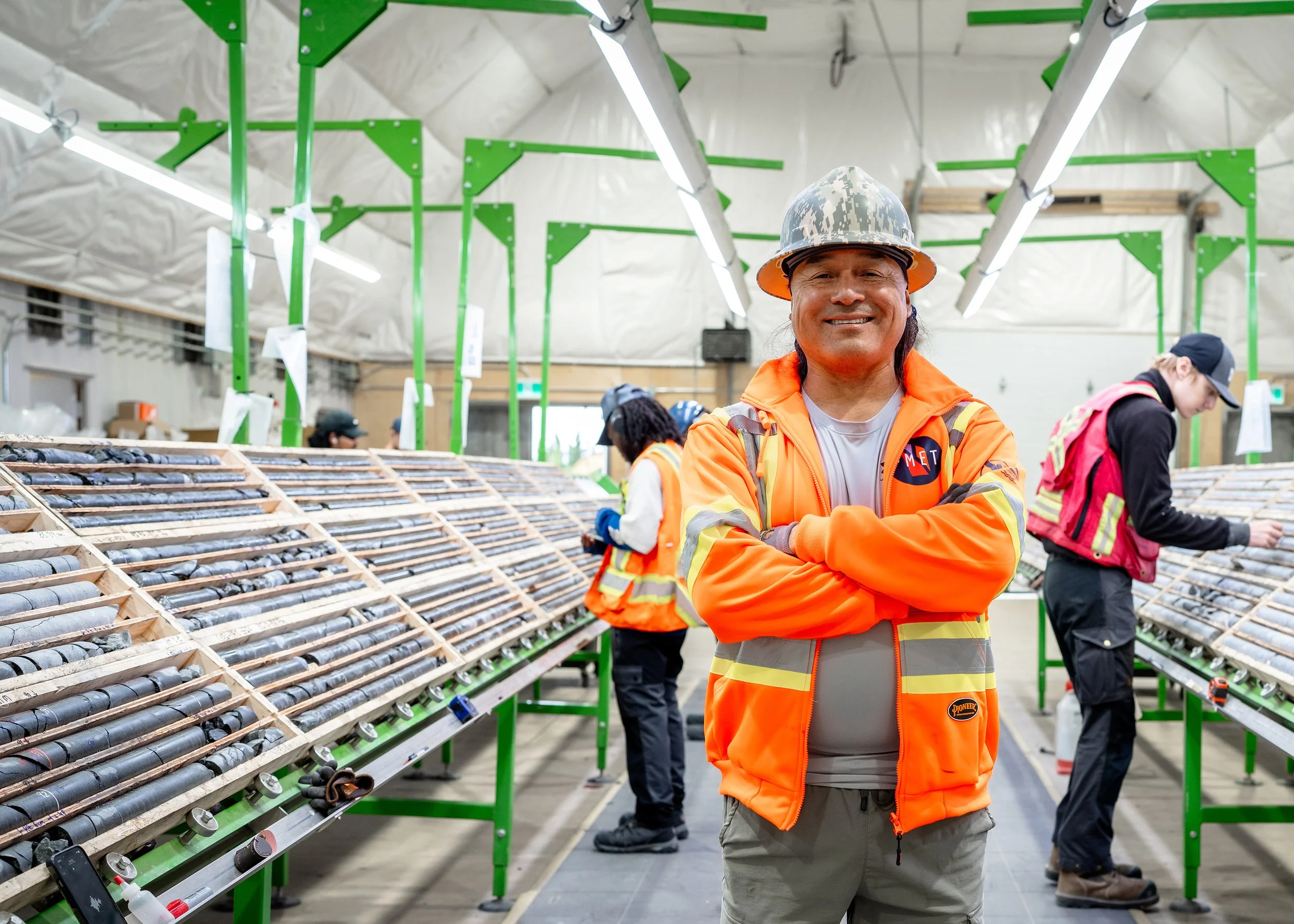 Worker in a hard hat and orange high-vis jacket smiling in the core shack