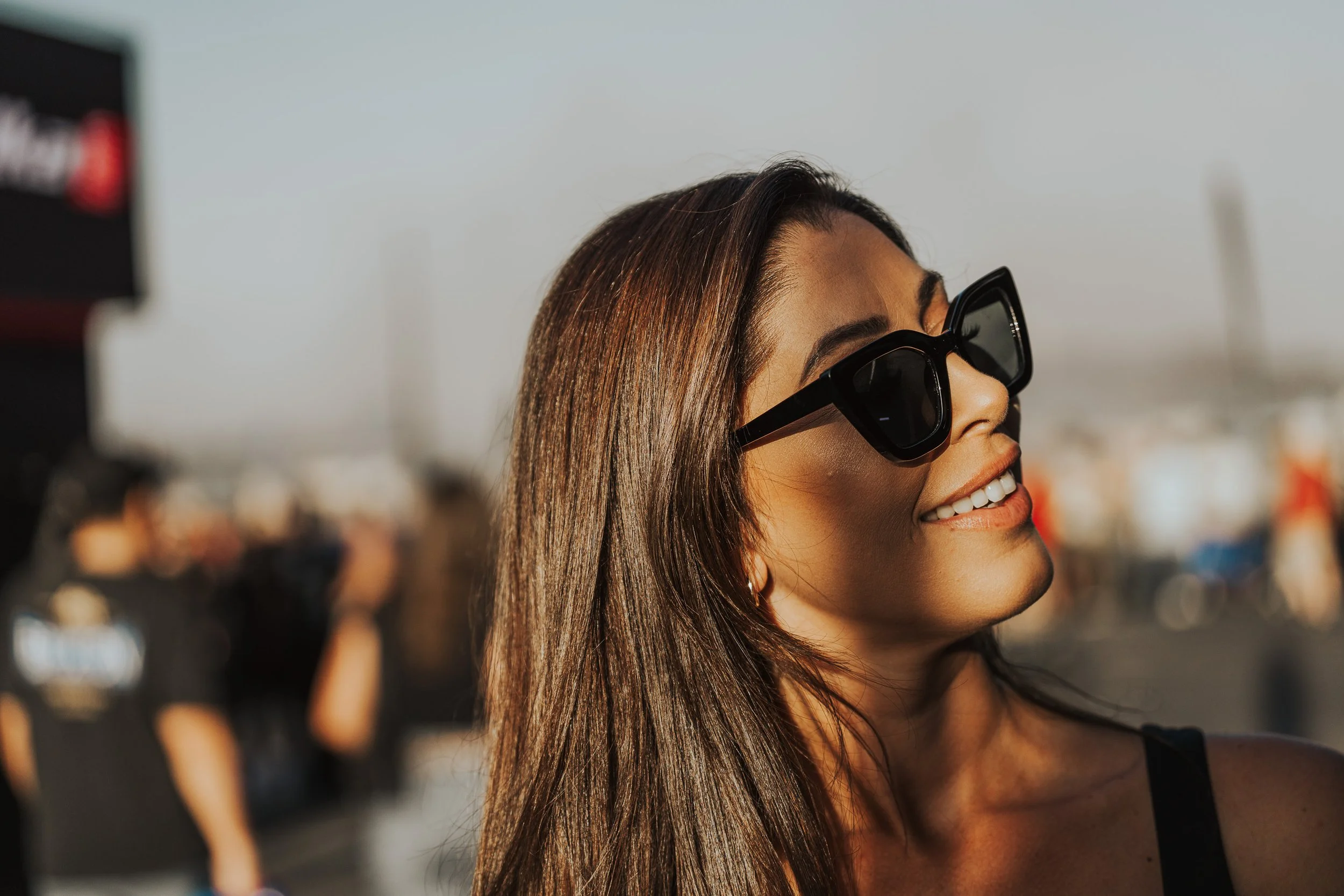 Smiling woman in sunglasses at golden hour in the pits