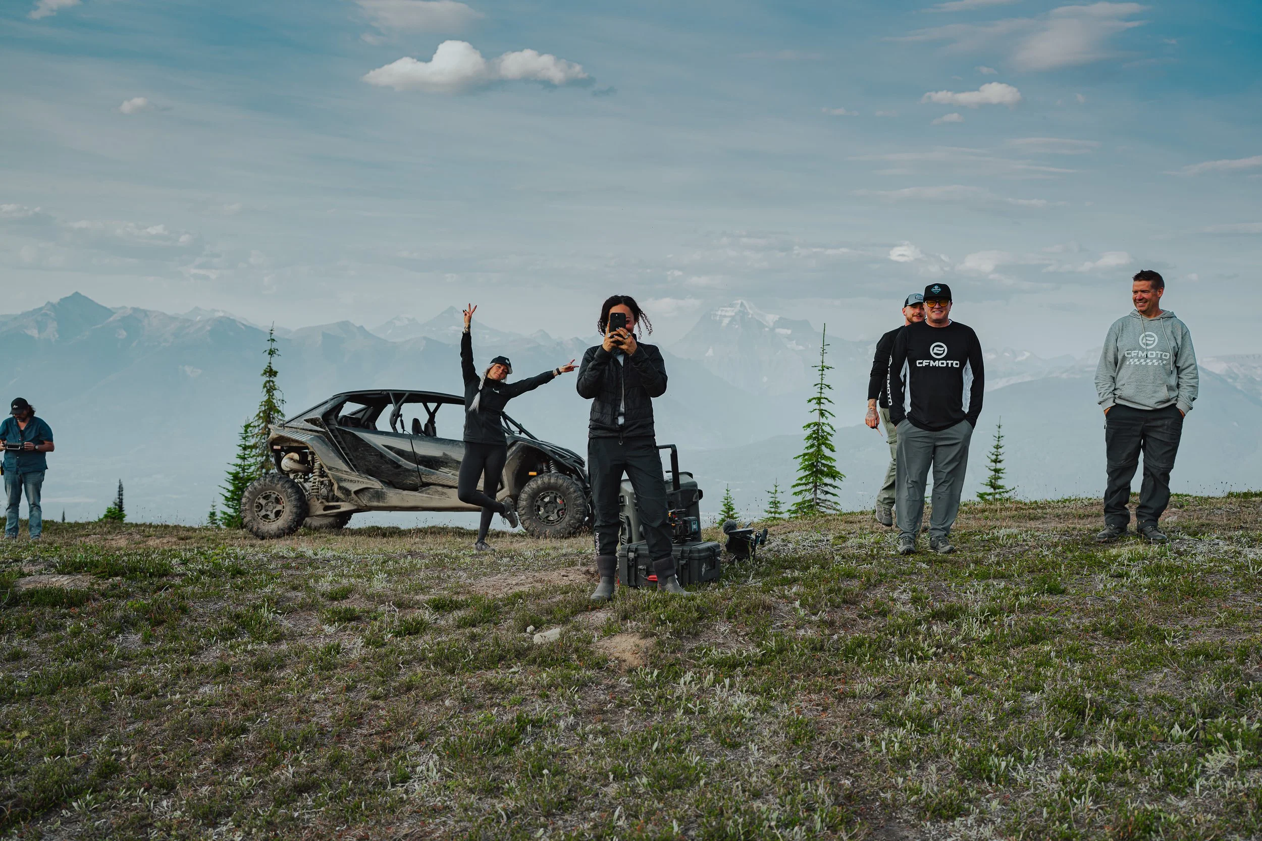 Film crew at work around a CFMOTO side-by-side on a mountain meadow