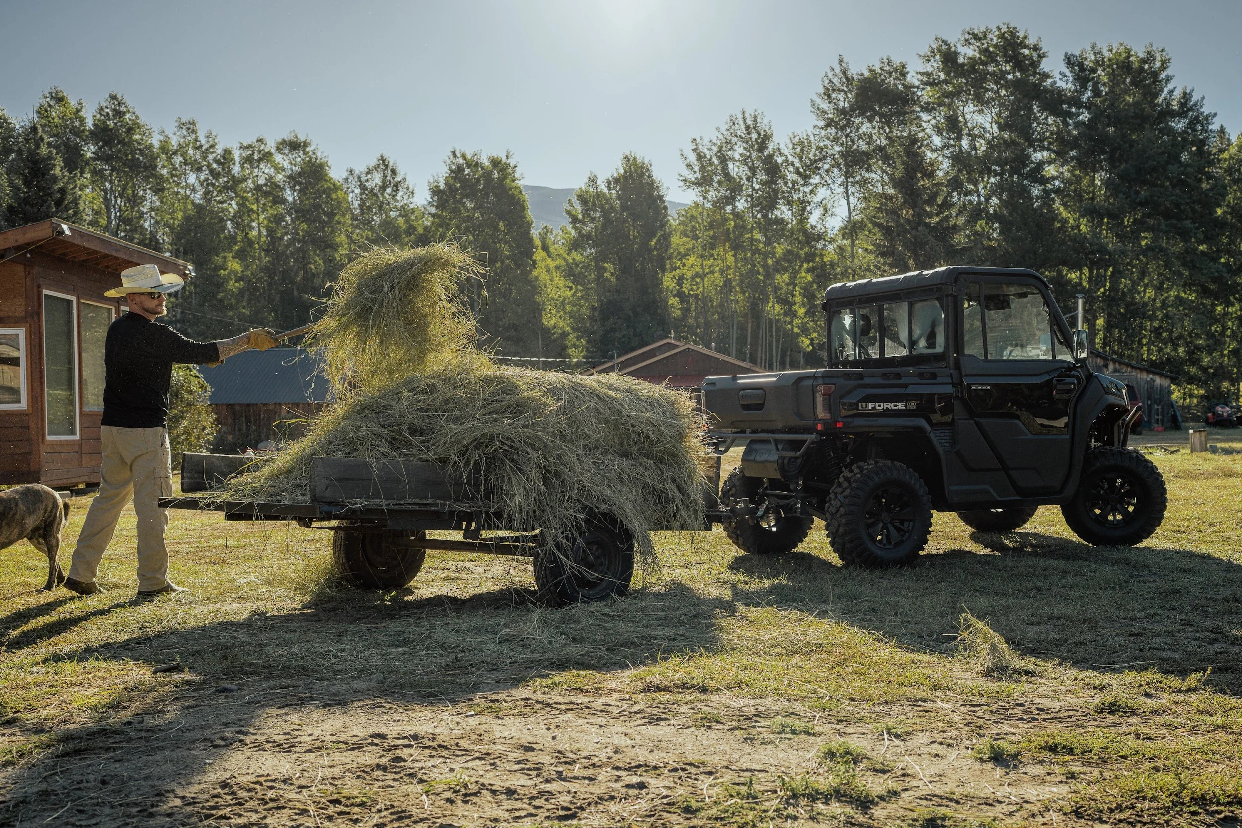 A rancher unloads hay from a trailer hitched to a CFMOTO UFORCE.