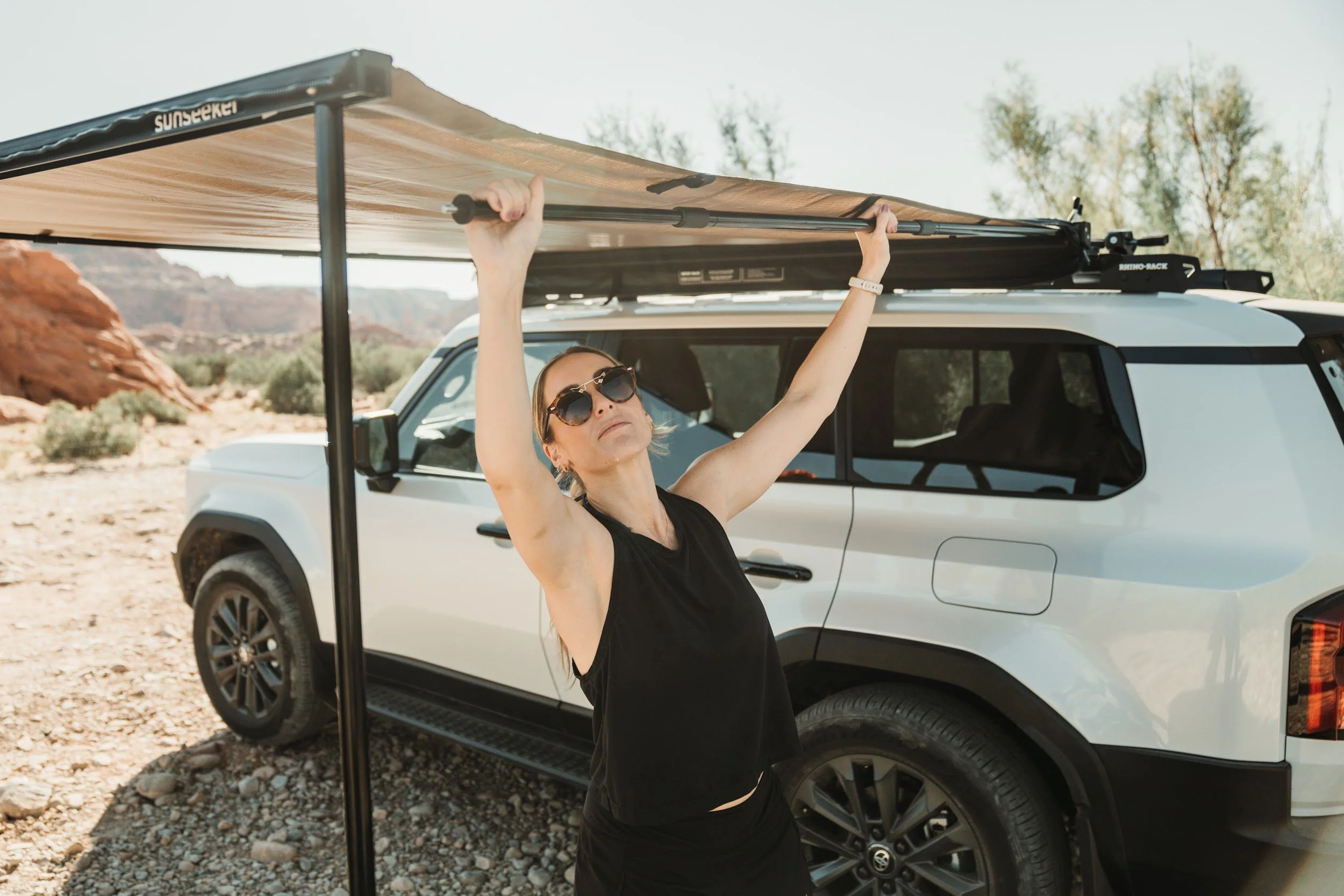 Woman setting up a Rhino-Rack awning on the side of a Land Cruiser in the Utah desert.
