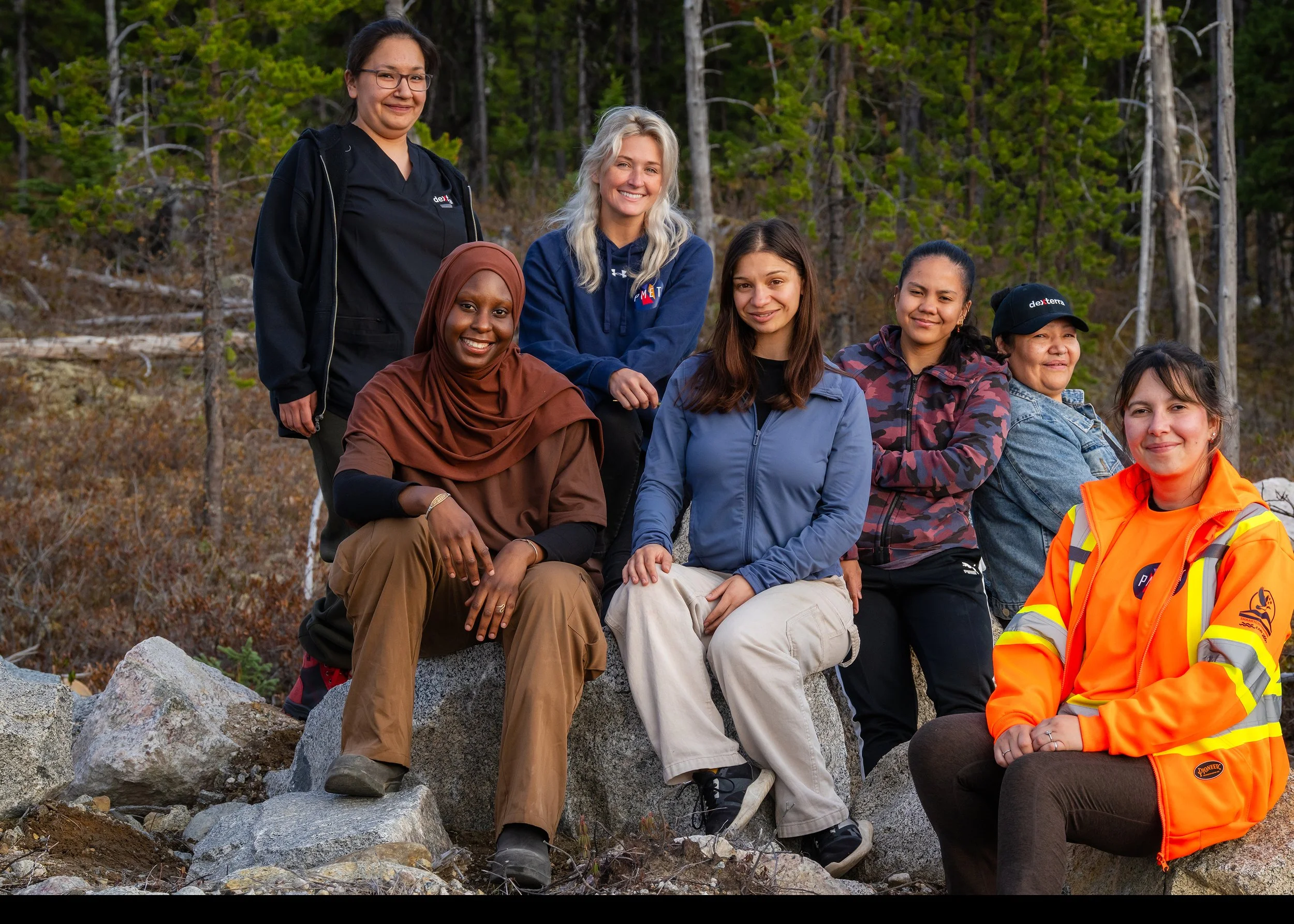 Seven women from the camp team sitting together on the rocks
