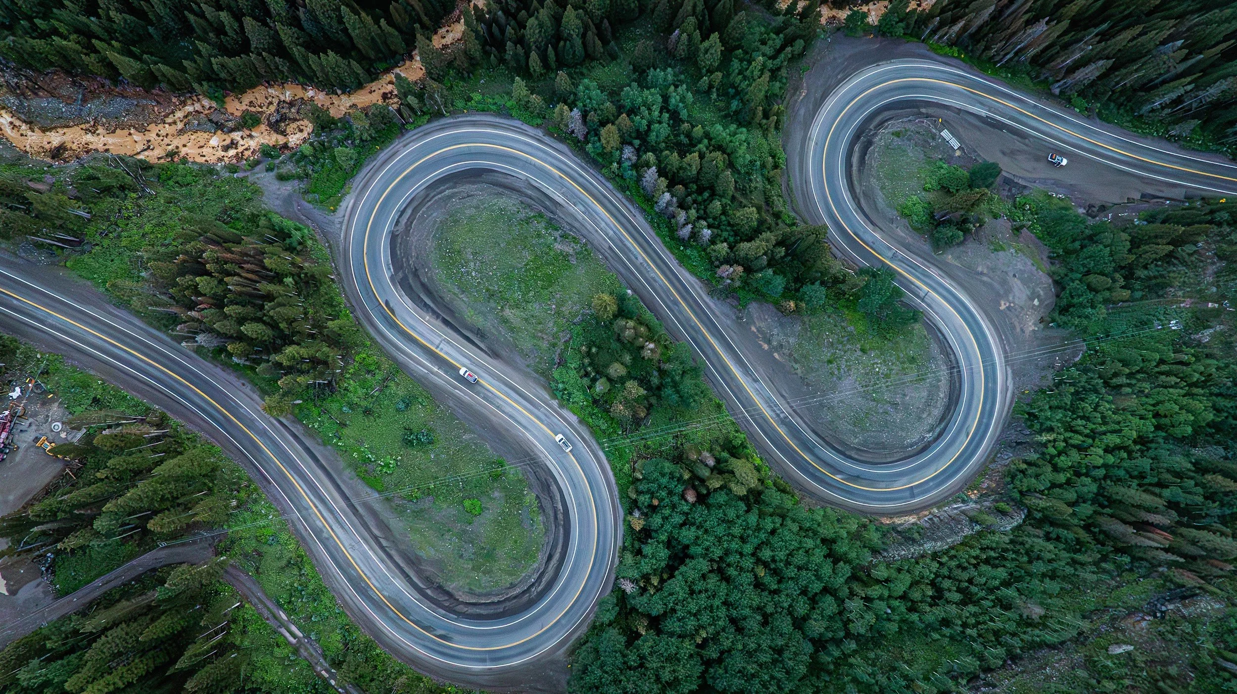 Aerial view of highway switchbacks cutting through the forest in Colorado.