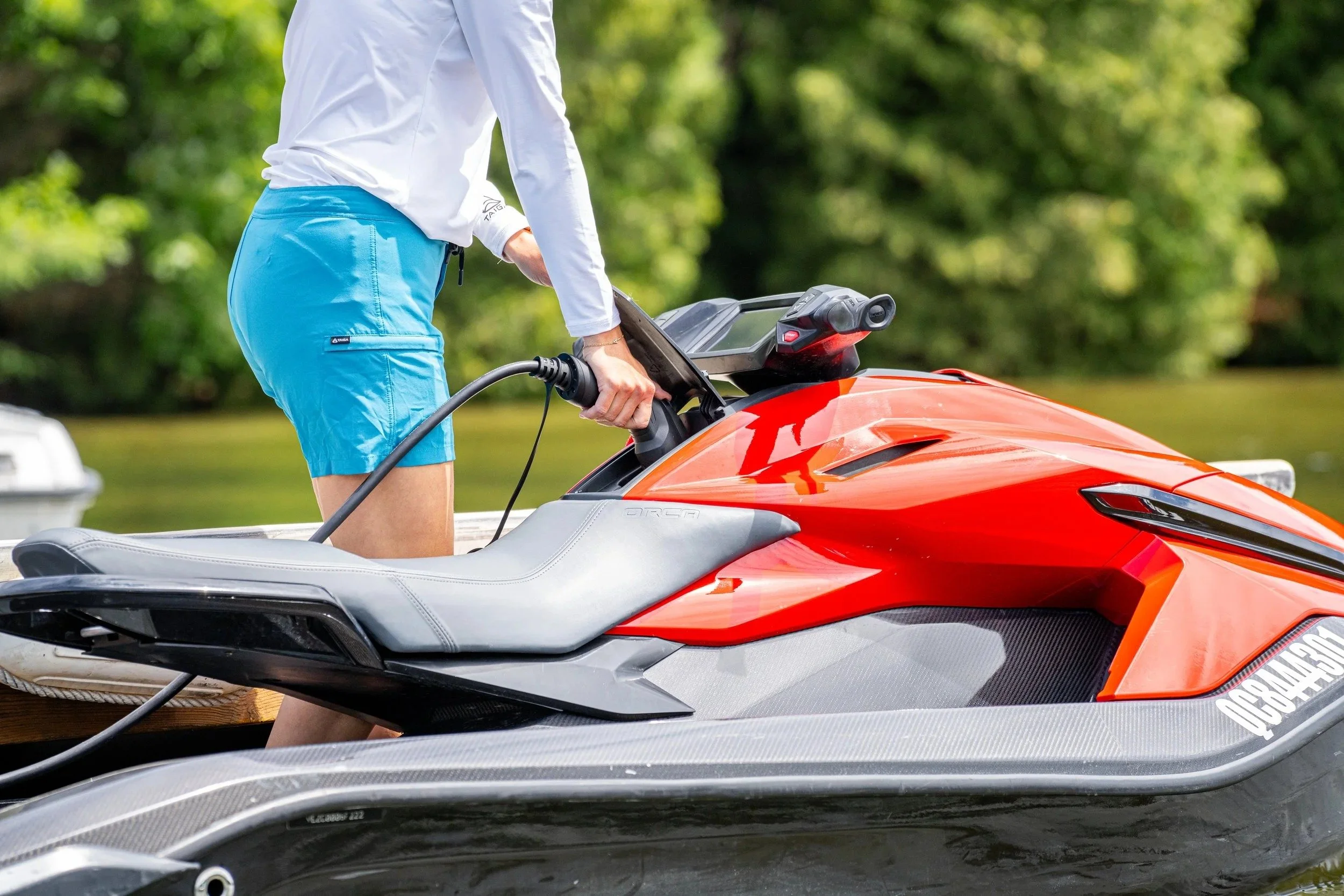 Rider plugging a charger into an orange Taiga Orca at the dock