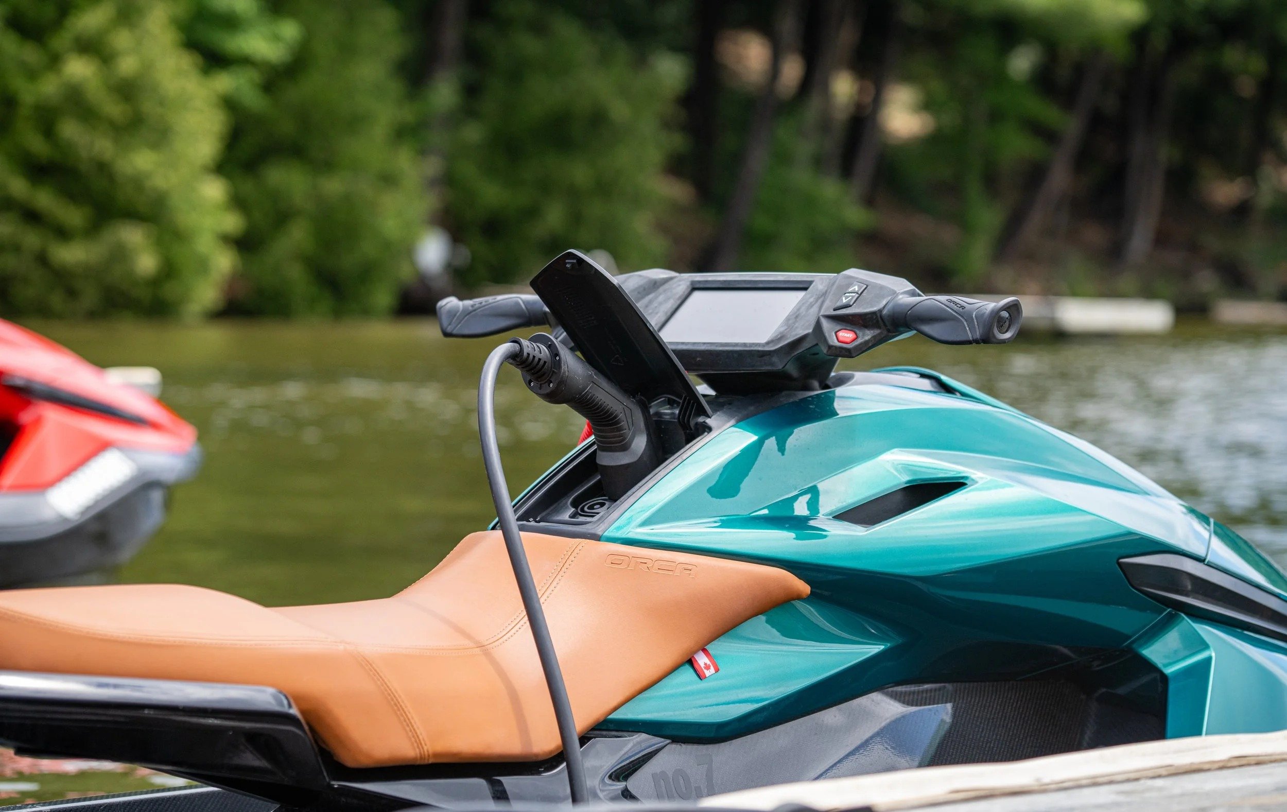 Teal Taiga Orca electric personal watercraft plugged in at the dock