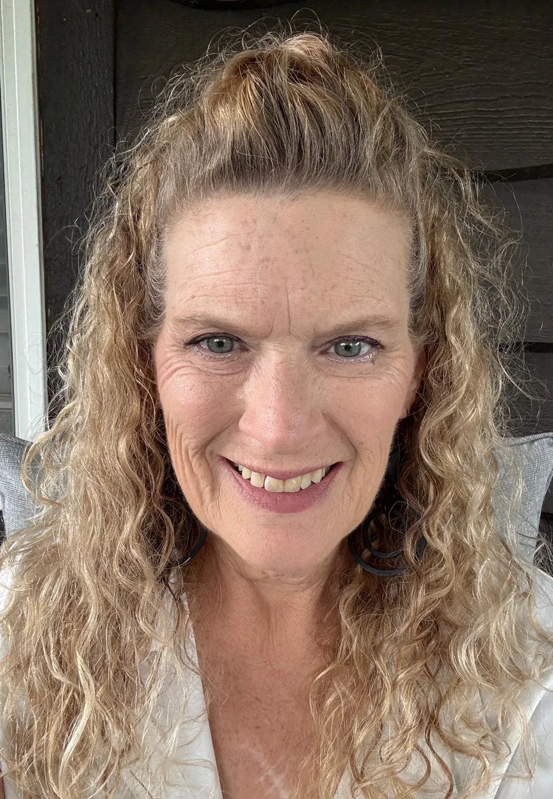 Smiling woman with long curly blonde hair looking at the camera.