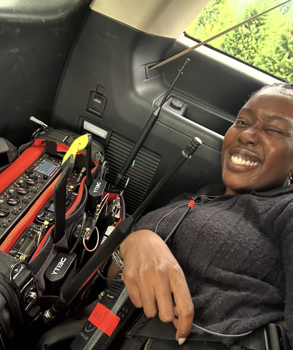 Woman smiling and relaxing inside a vehicle next to radio communication equipment and antennas.
