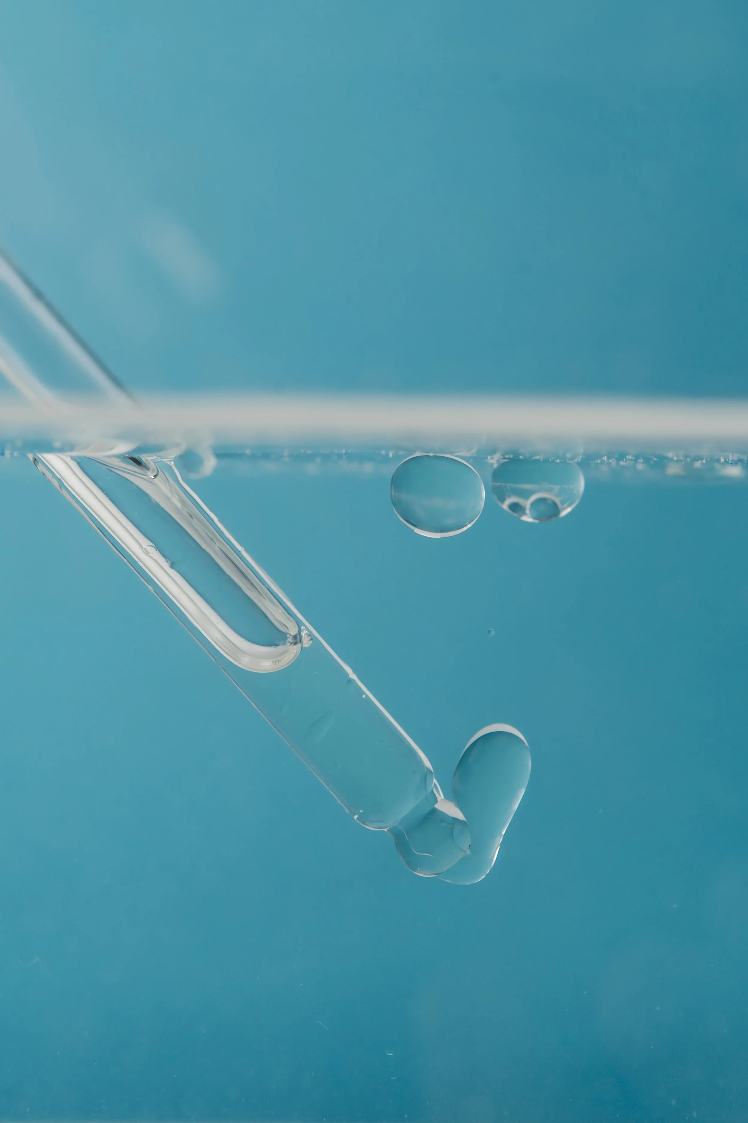 Close-up of a glass object with some water droplets on it against a blue background.
