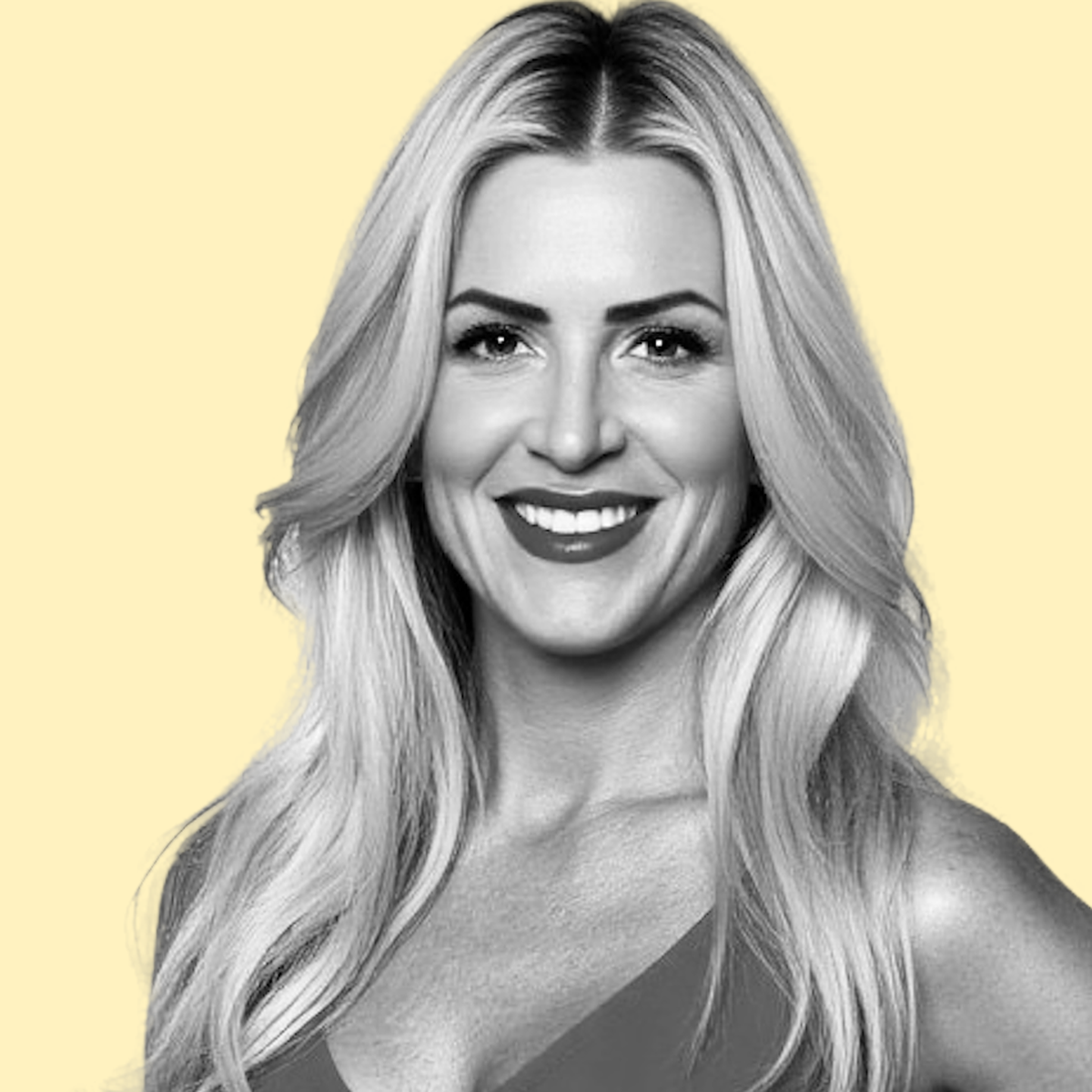 Black-and-white portrait of a smiling woman with long wavy blonde hair, set against a pale yellow background.
