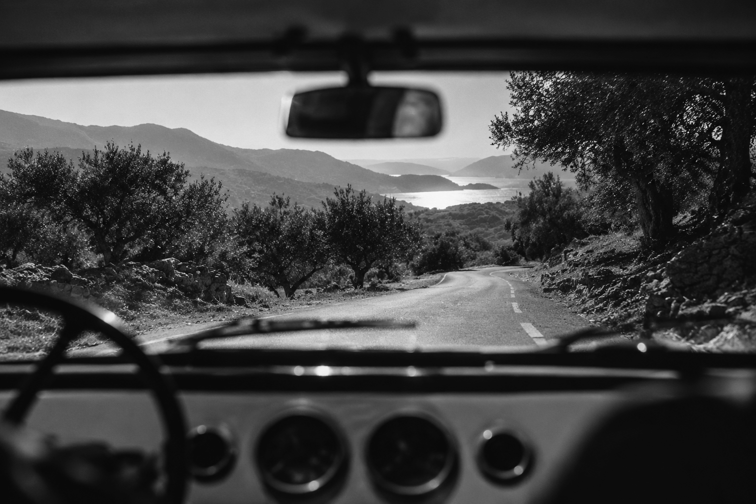 Winding road viewed through the windshield of a vintage car