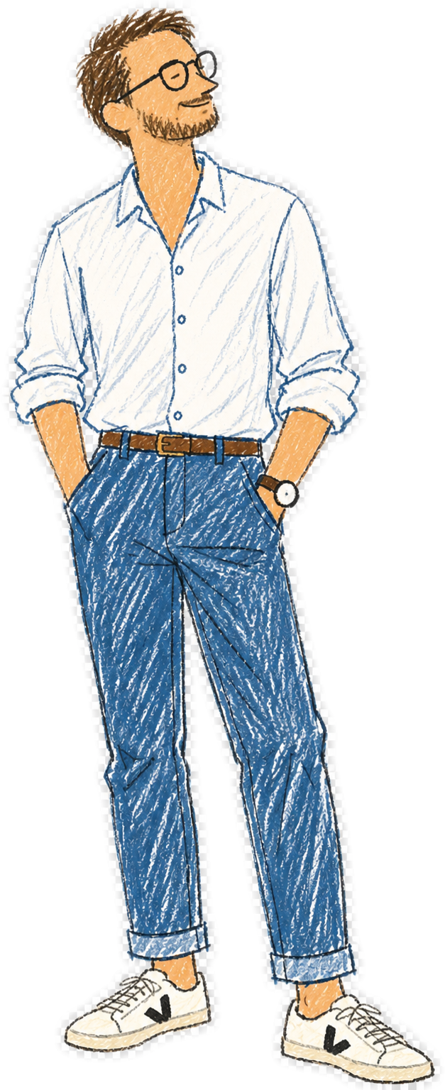 A man with glasses and a beard, wearing a white button-up shirt, blue jeans, sneakers, and a wristwatch, standing with hands in pockets, smiling and looking to his left.