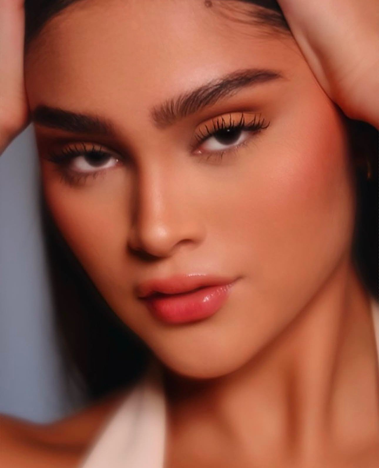 Close-up of a woman's face with her hand resting on her forehead, showing her eyebrows, eyes, nose, and lips.