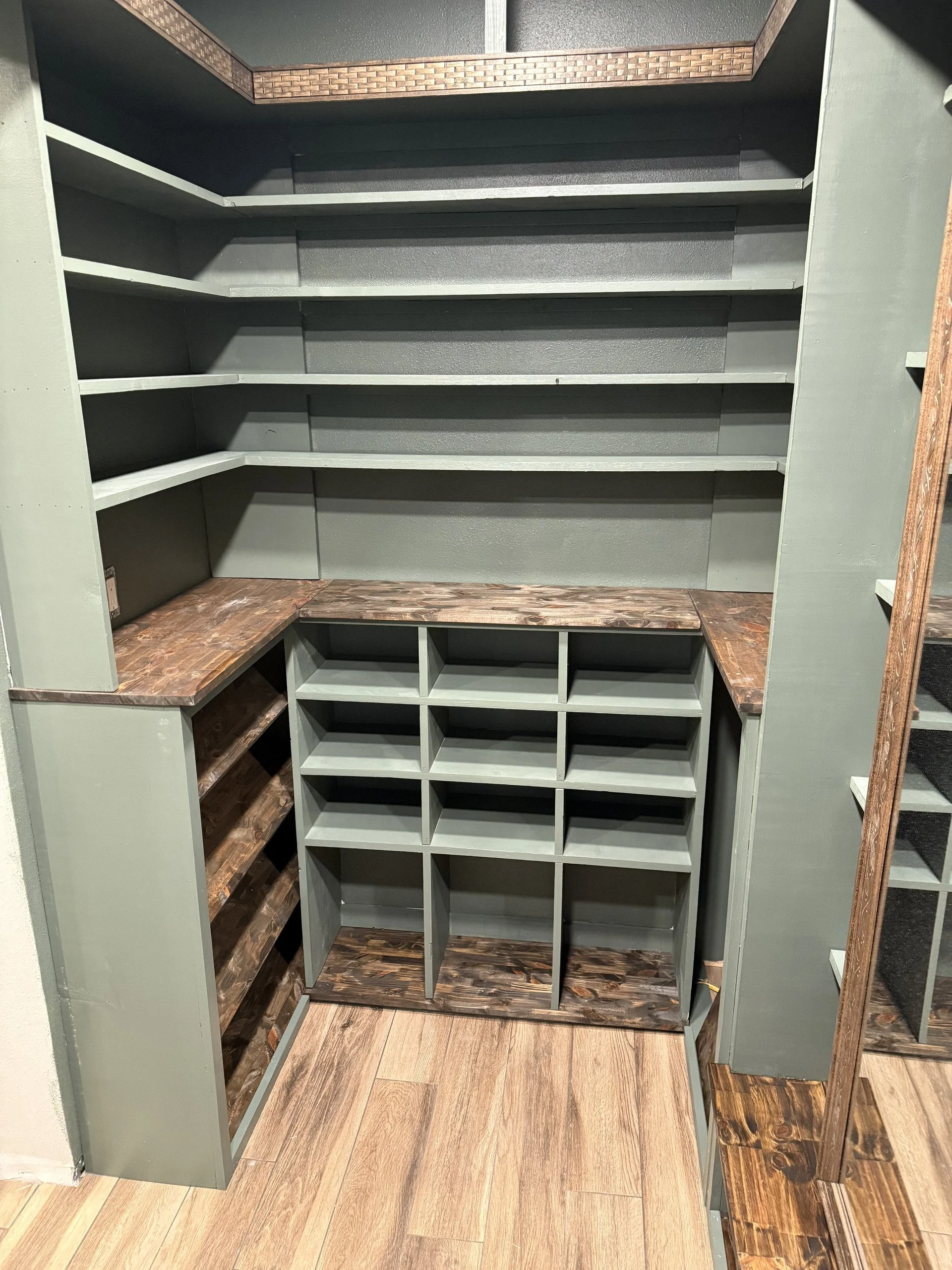 A built-in shelving unit and a shoe rack at the bottom, surrounded by wood-paneled surfaces and a wood or laminate floor.