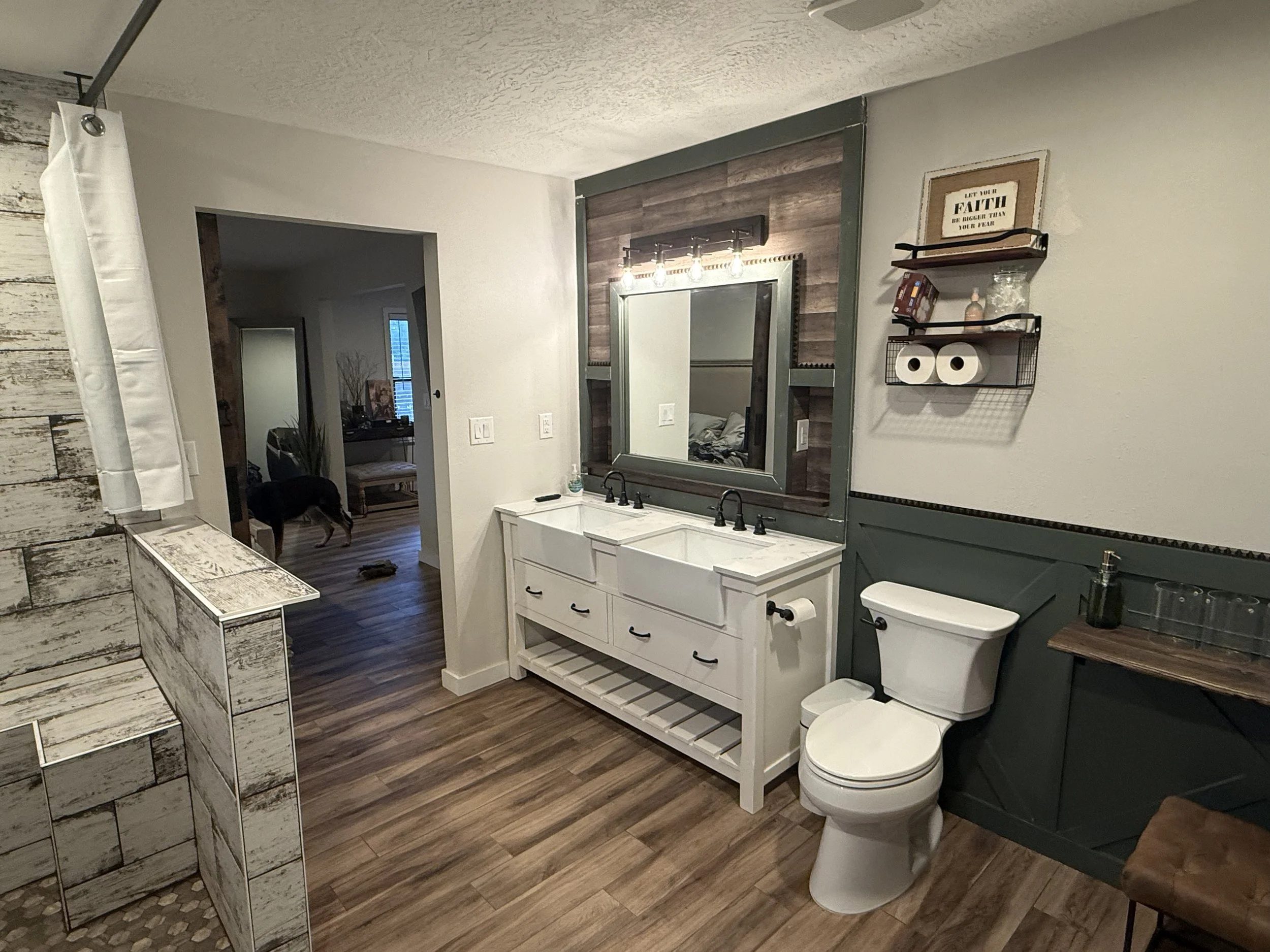 A bathroom with a vanity mirror, a sink, a toilet, and various decor and shelves on the wall.