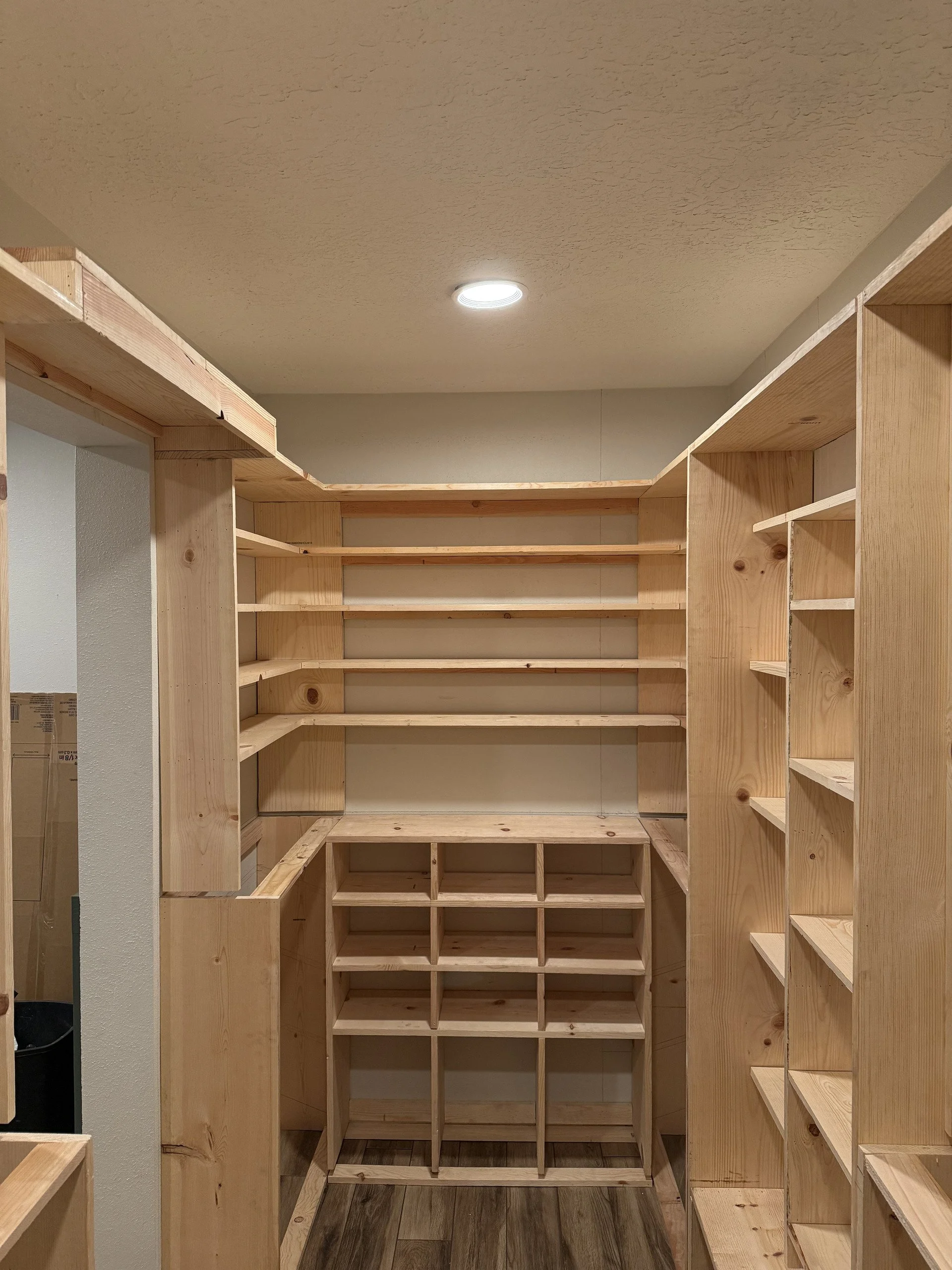 Empty wooden closet shelves with a ceiling light.