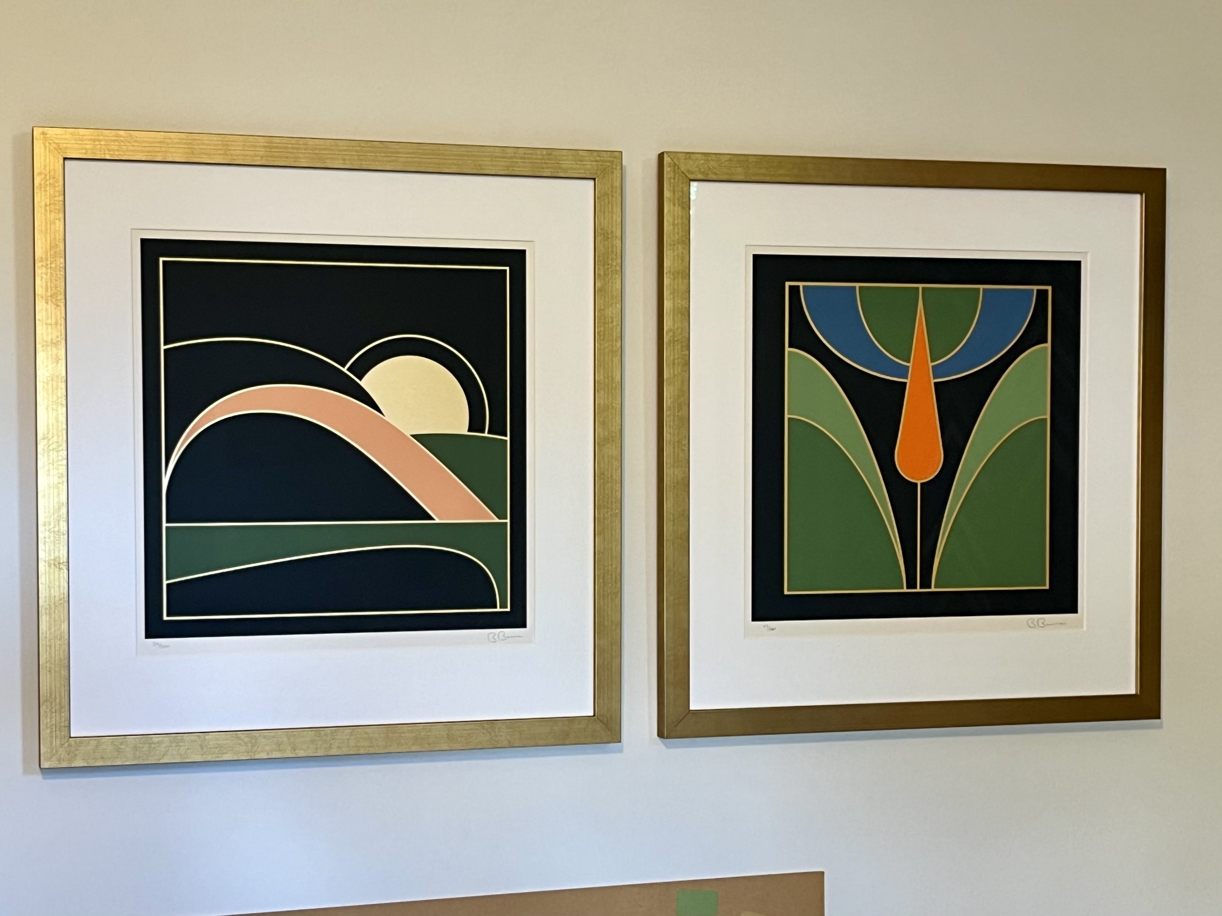 Two framed abstract art pieces with geometric shapes, bold lines, and vibrant colors, hanging on a wall.