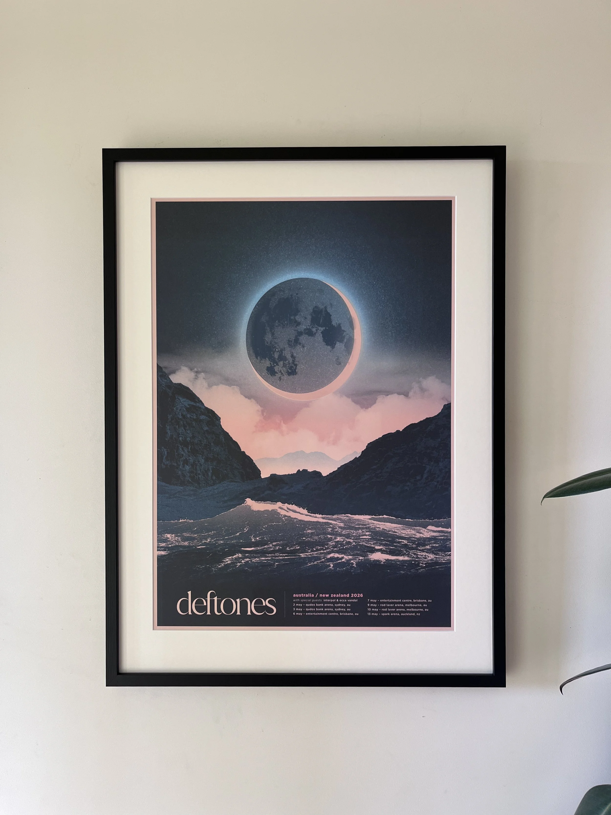 A framed concert poster featuring a lunar eclipse over mountains and clouds, promoting Deftones' 2026 tour in Australia and New Zealand. Artwork by Simon Marchner