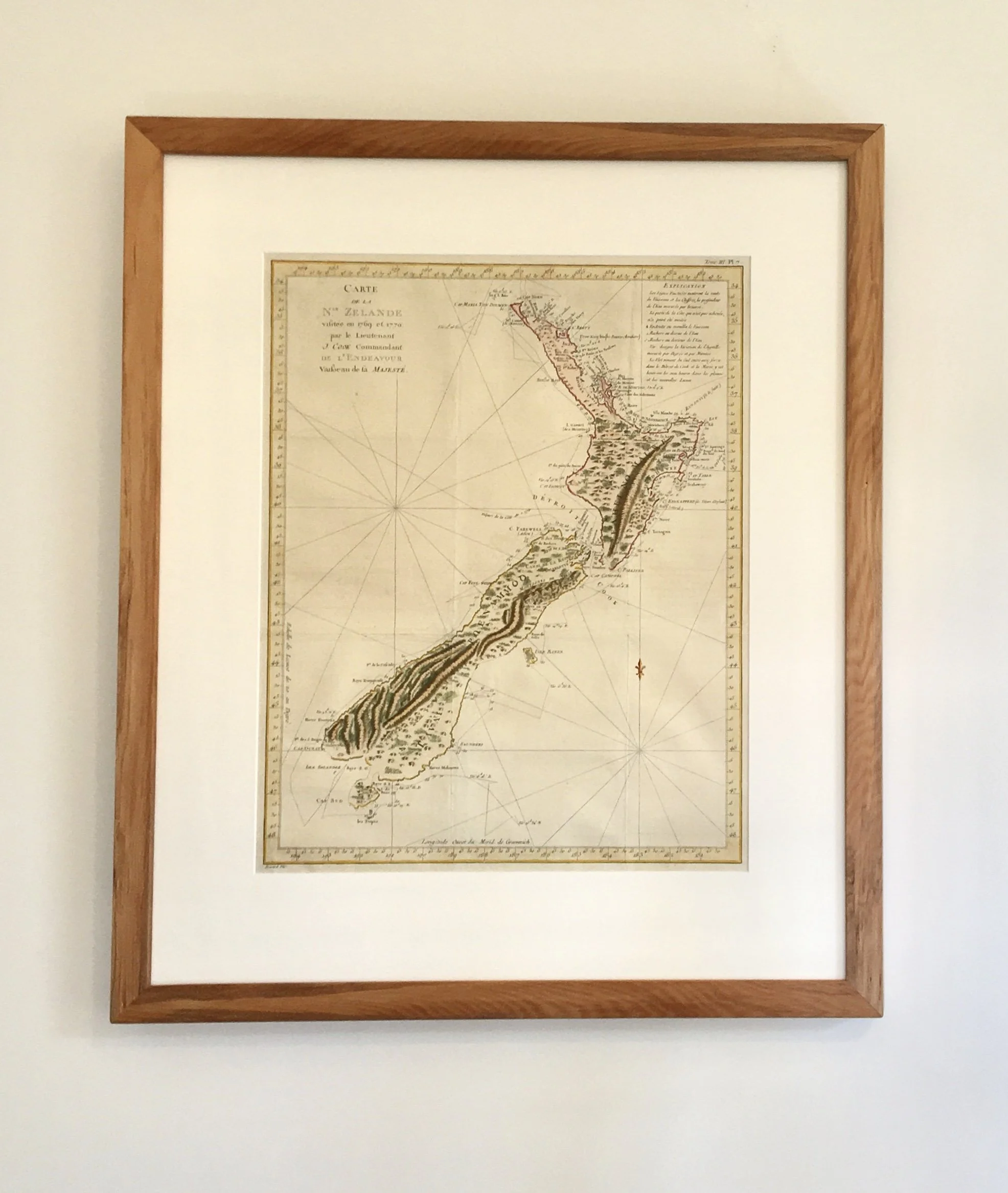 Framed vintage map of New Zealand on a white wall.