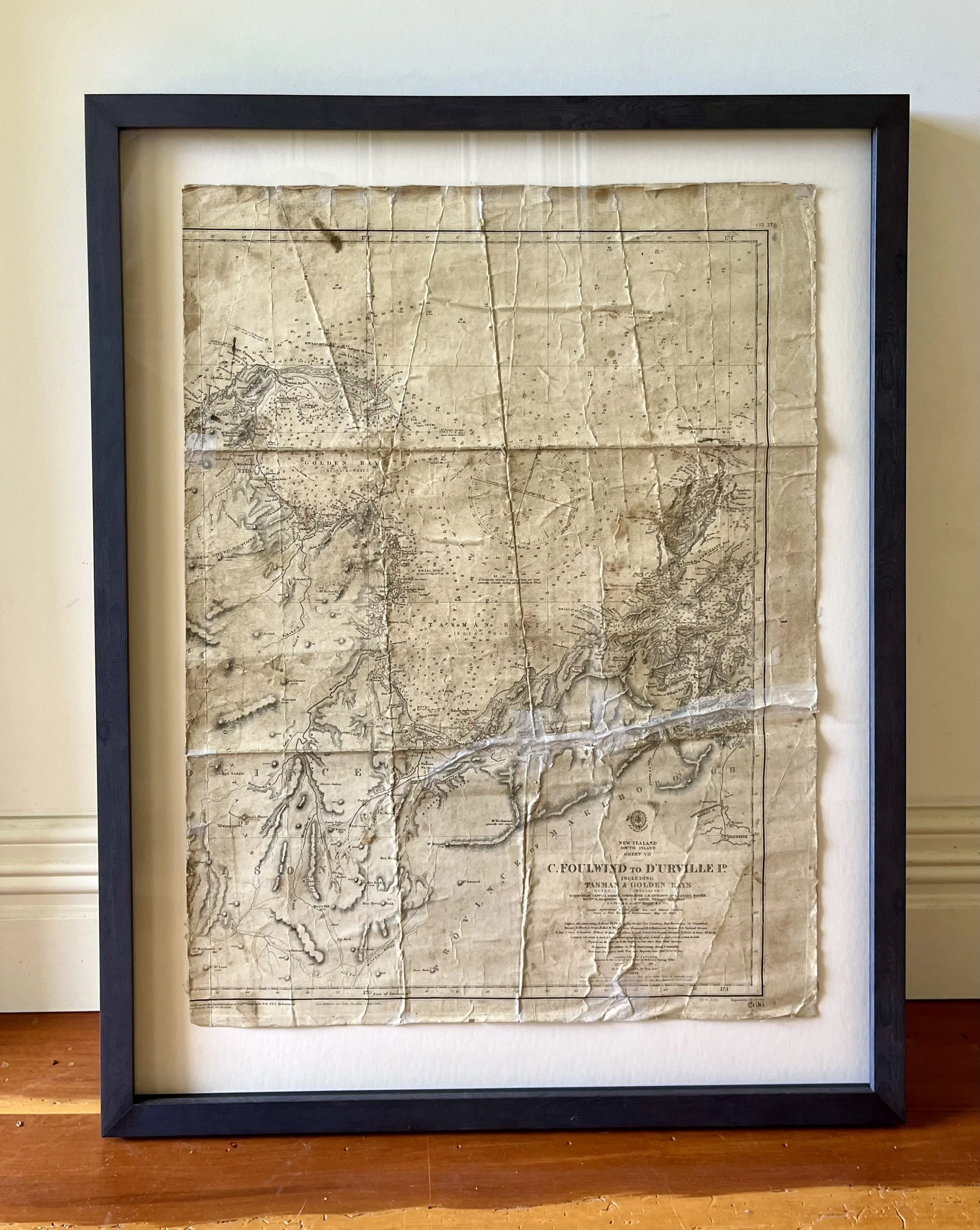 Framed antique map with creases and worn edges, titled "C. Foulwind to Durville I. Including Tasman & Golden Bays" and showing geographical features of New Zealand.
