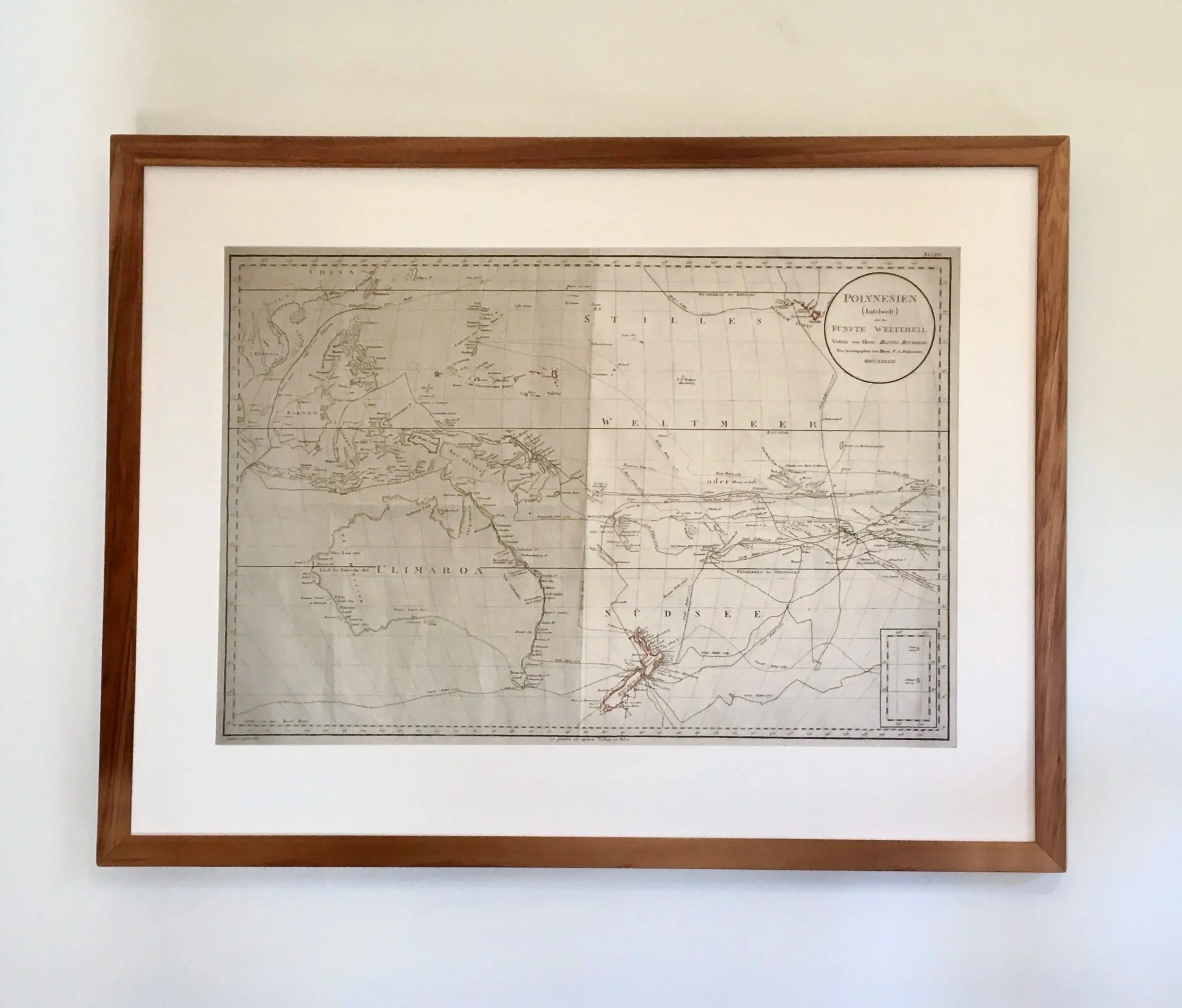An old map framed with reclaimed Rimu and hung on a white wall.
