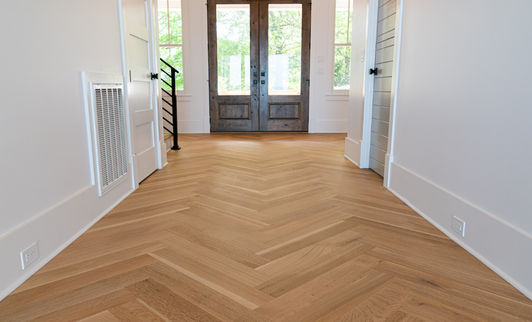 Herringbone hardwood flooring, front door, and large window