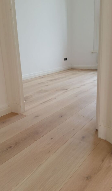 Empty room with light-colored wooden floors and white walls.