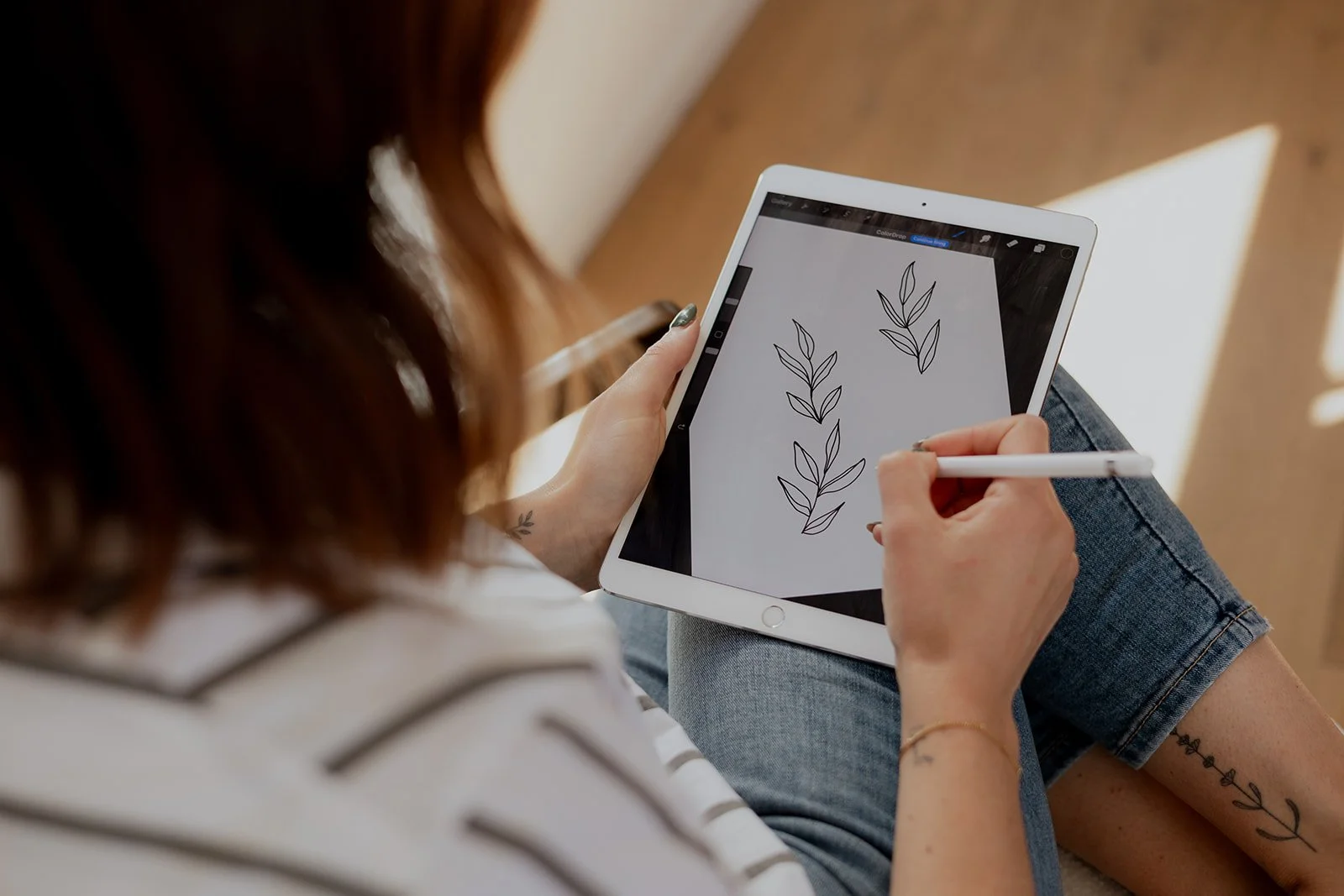 Person drawing leaf illustrations on a tablet with a stylus.