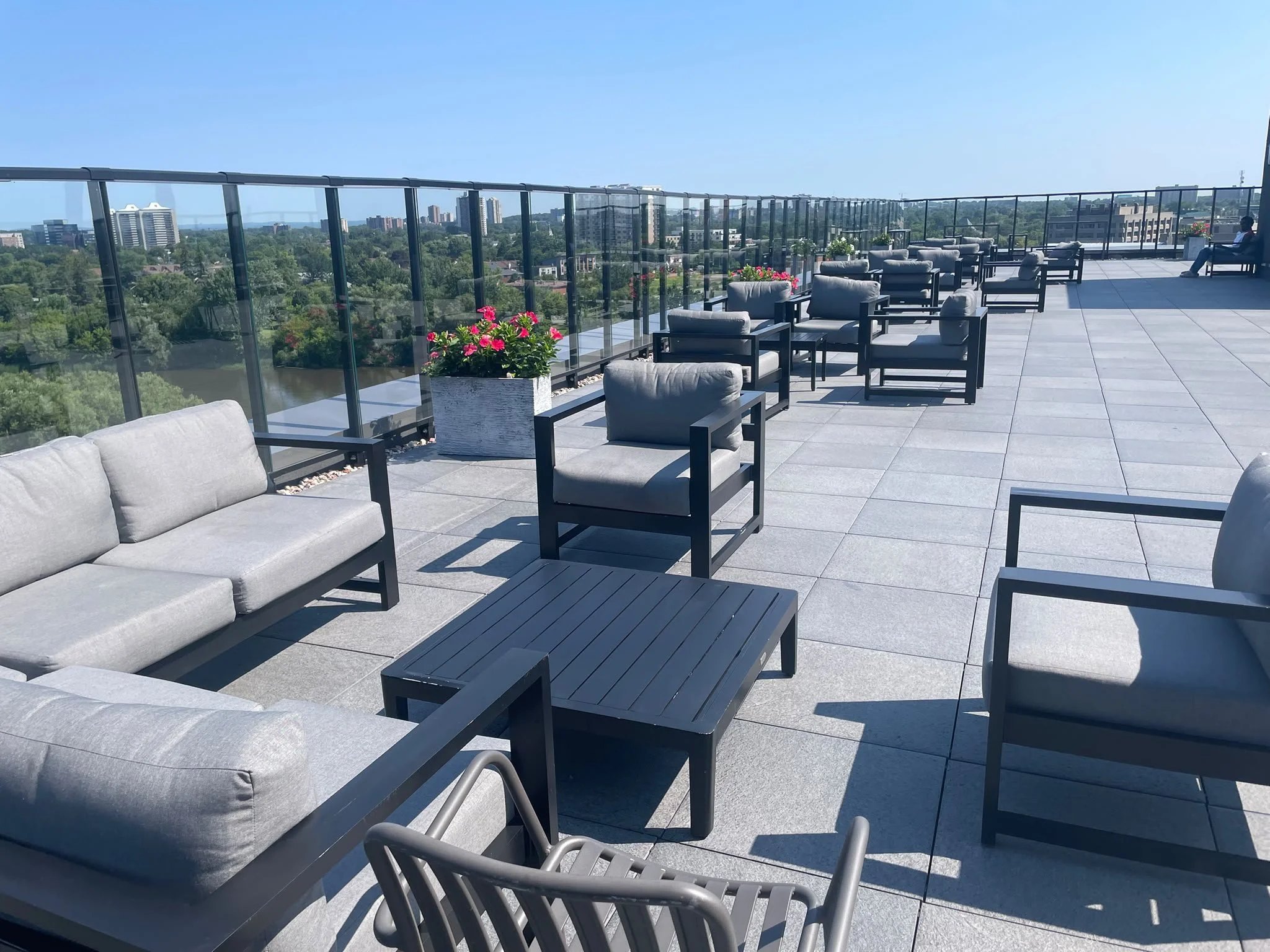 Rooftop terrace after cleaning, with lounge chairs, potted flowers, and a glass railing overlooking Ottawa.