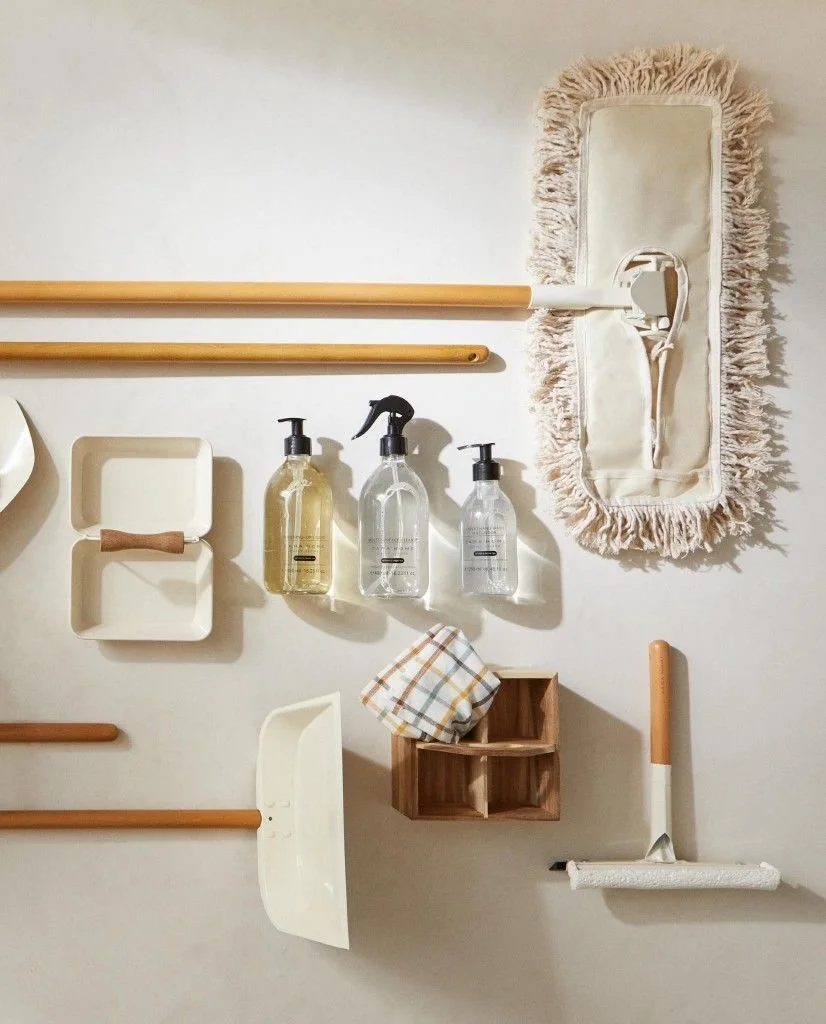 Organized wall with cleaning supplies, wooden rods, a mirror with fringe, and a storage box.