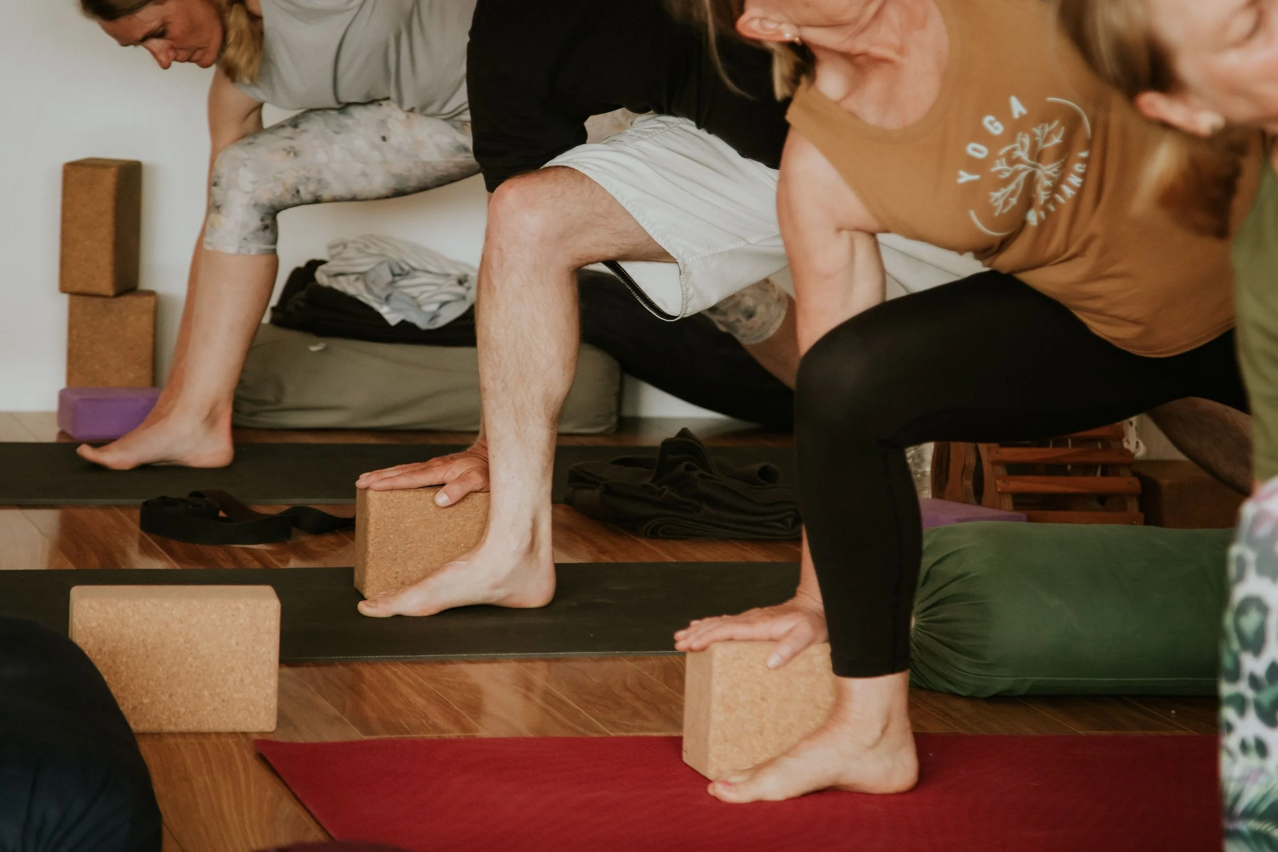 People practicing yoga in a room, using yoga blocks for support during a pose.