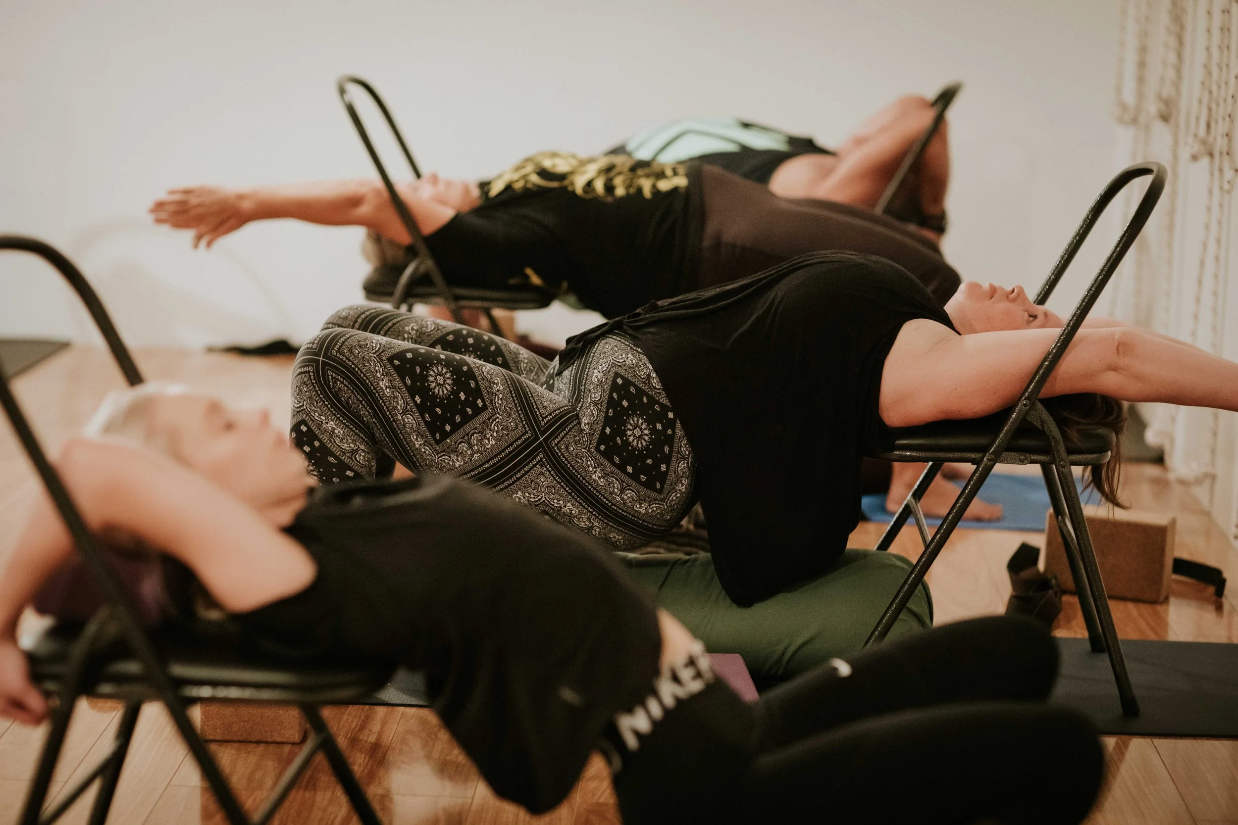 Students practising supported Iyengar Yoga poses using chairs at Yoga Whitianga.