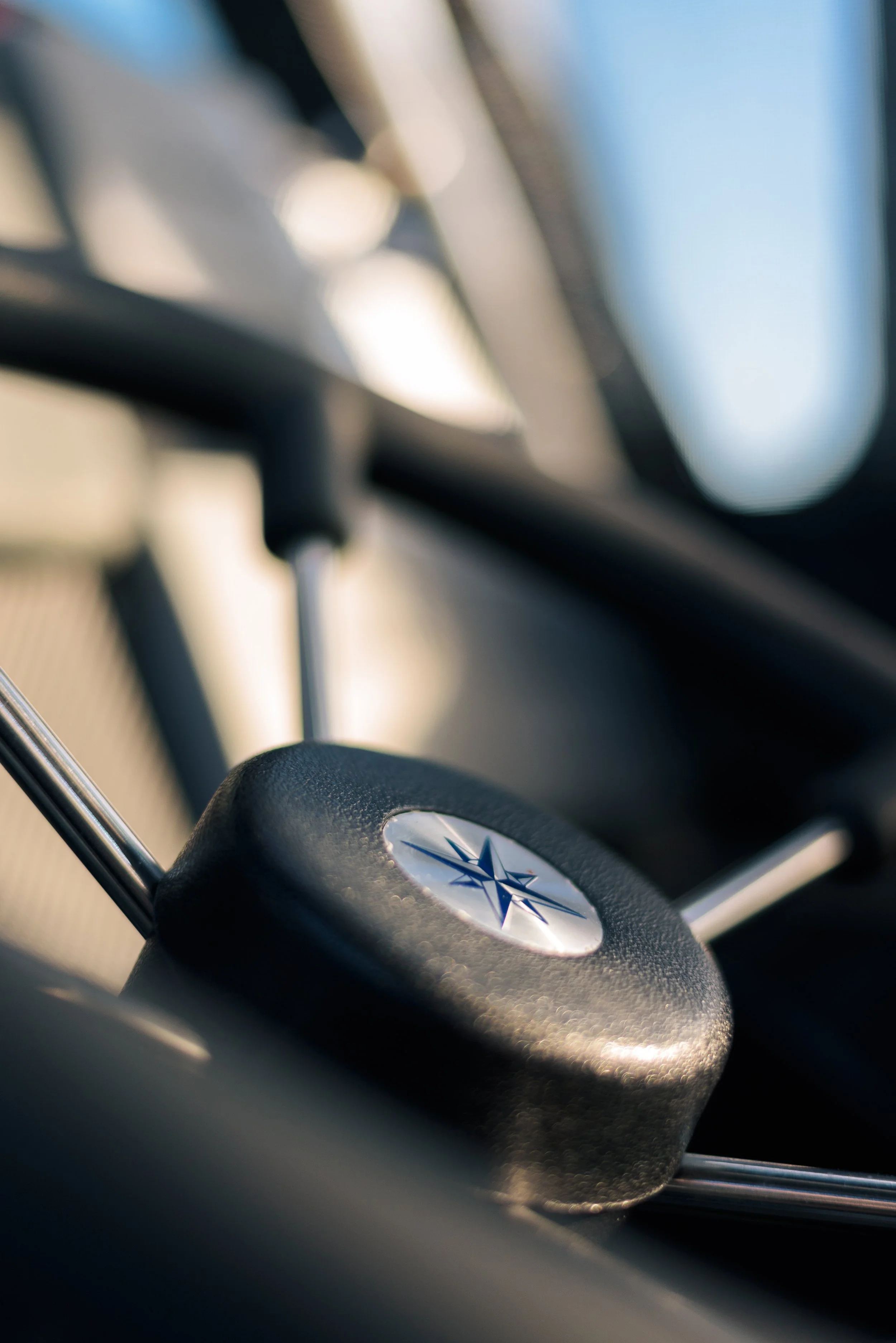 Close-up of a metallic steering wheel with a Subaru logo, partially visible, inside a vehicle.