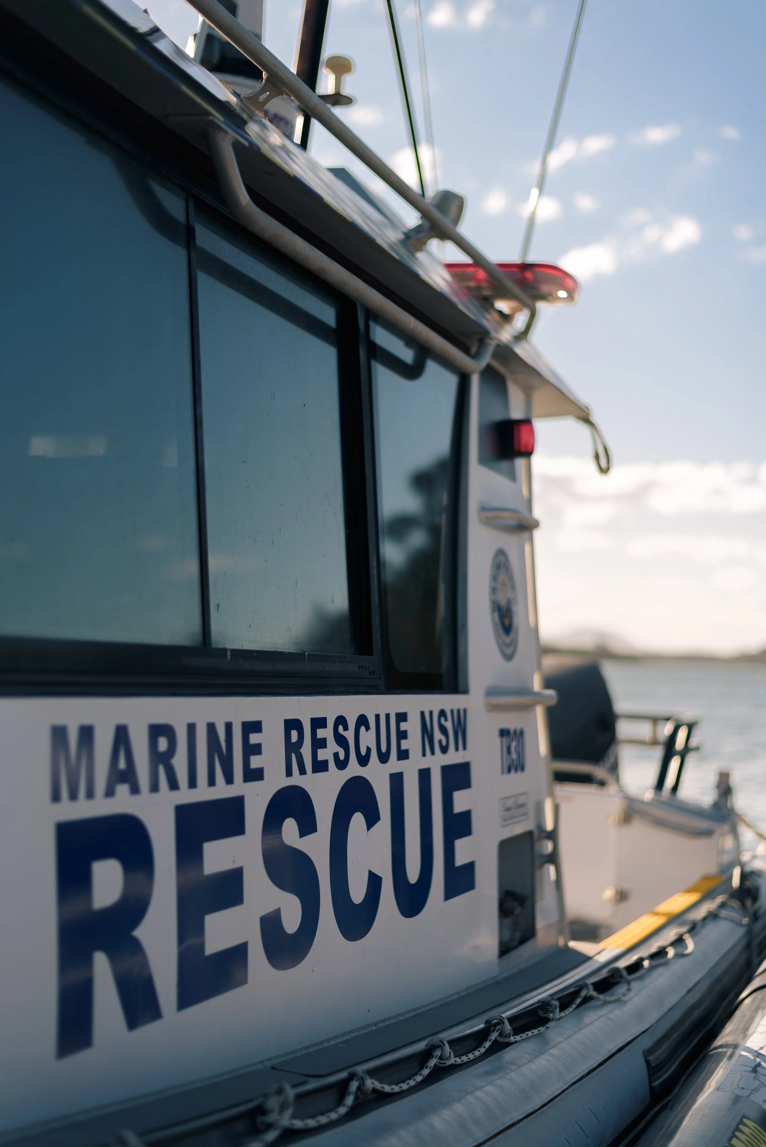 Close-up of a Marine Rescue NSW vehicle with a part of its sign visible, showing the words "MARINE RESCUE NSW" and "RESCUE" in bold blue letters, with a focus on the side and equipment on top of the vehicle.
