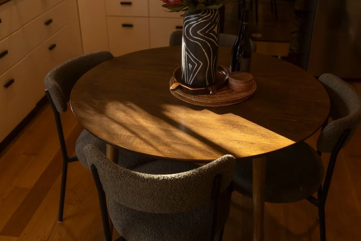 Timber dining table and upholstered chairs in afternoon sunlight