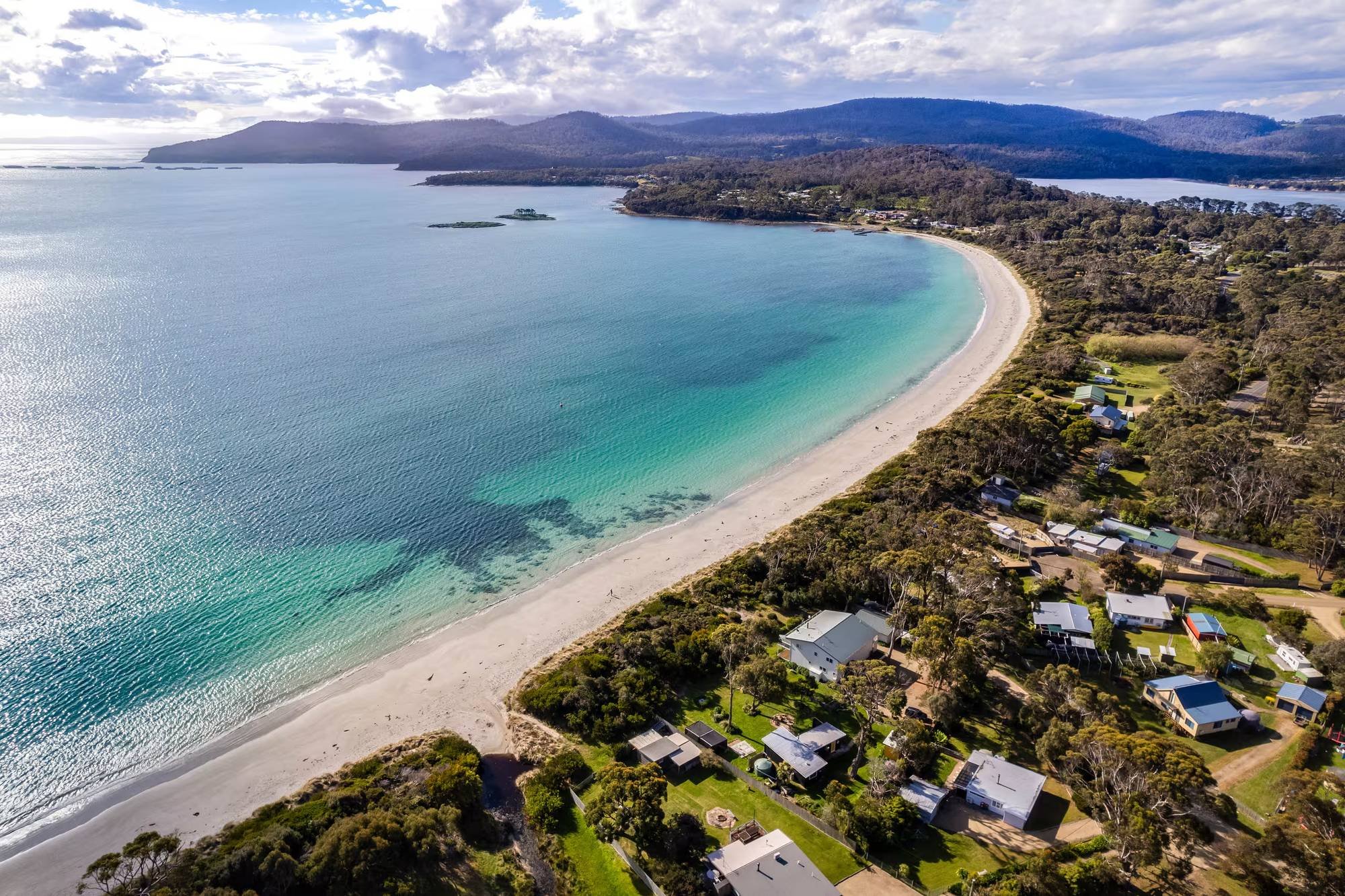 Aerial view of White Beach on the Tasman Peninsula, with turquoise water and hills beyond