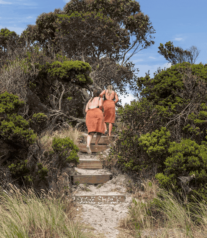 Two women walking up the timber steps over the dunes to White Beach