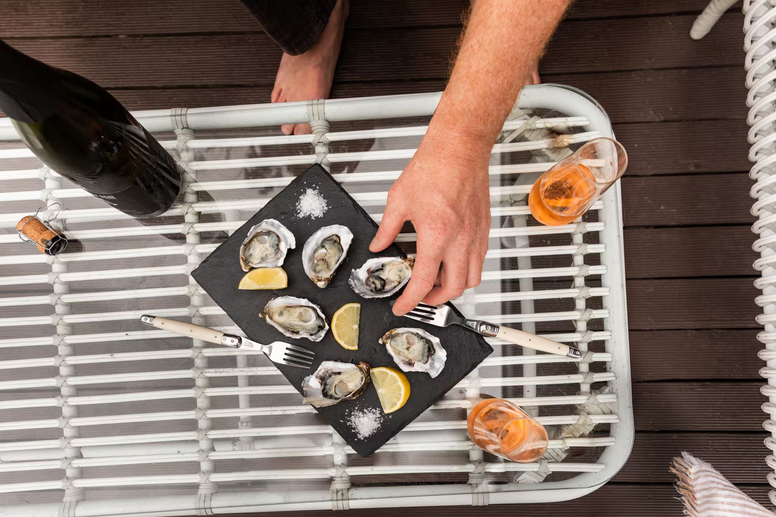 Fresh oysters with lemon and two glasses of rosé on the timber deck